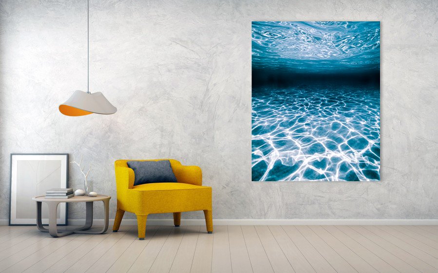 Modern abstract metal print photograph of light and texture casted from the ocean surface to the sea floor hung on a living room wall.