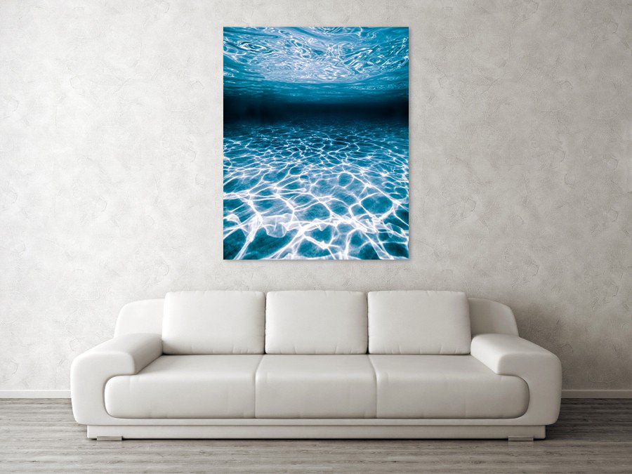 Modern abstract metal print photograph of light and texture casted from the ocean surface to the sea floor hung above a couch.