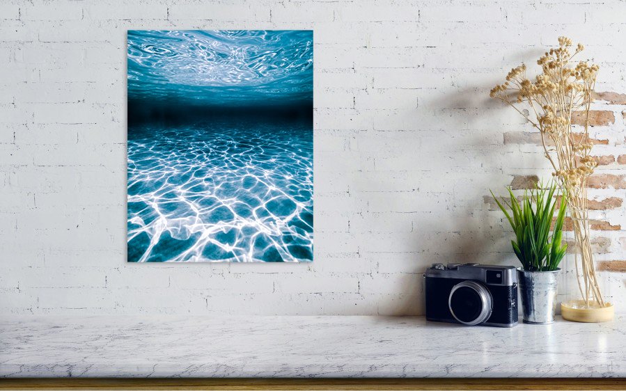 Modern abstract metal print photograph of light and texture casted from the ocean surface to the sea floor mounted on a wall above a counter.