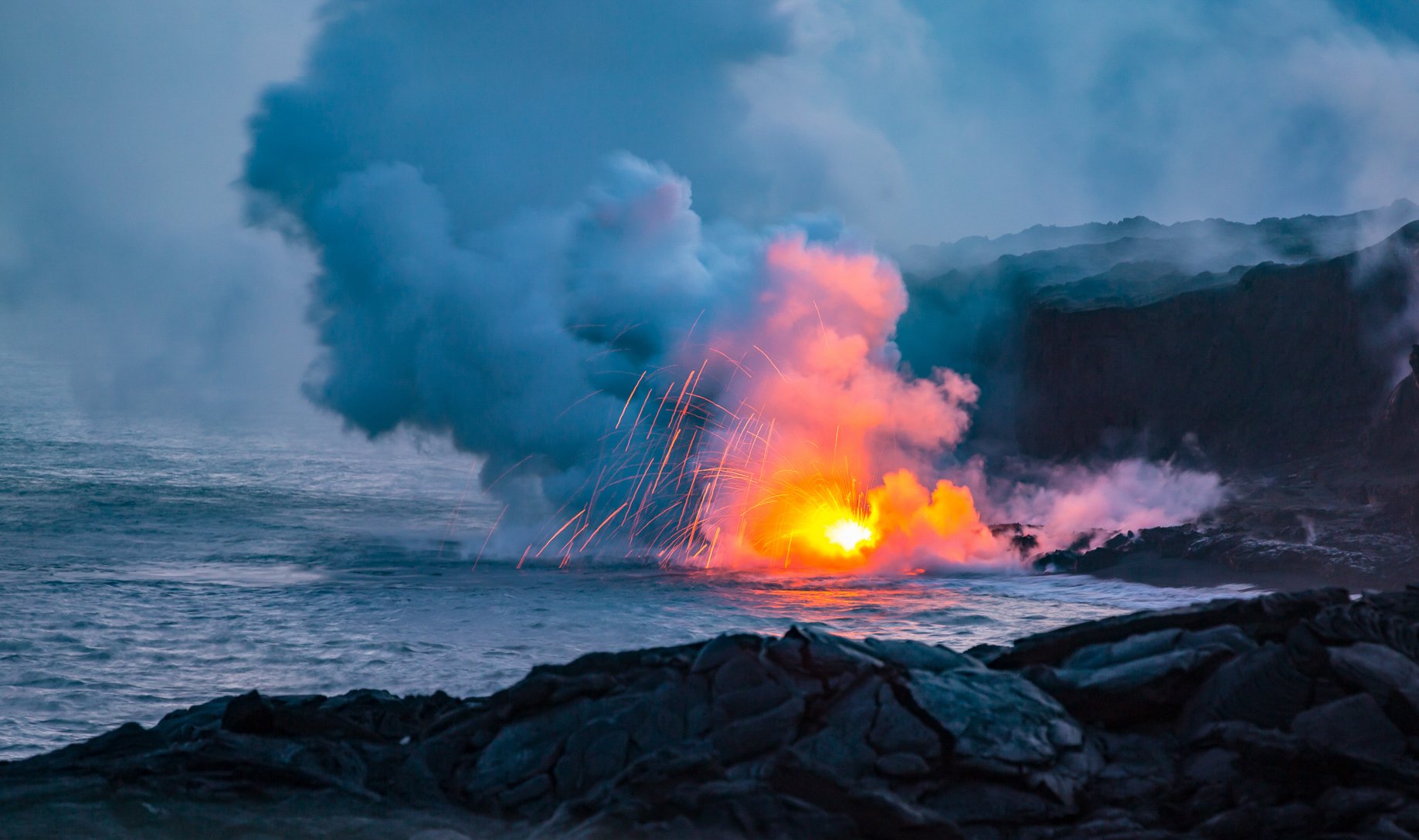 lava pours into the ocean creating an explosion of light when touching the water