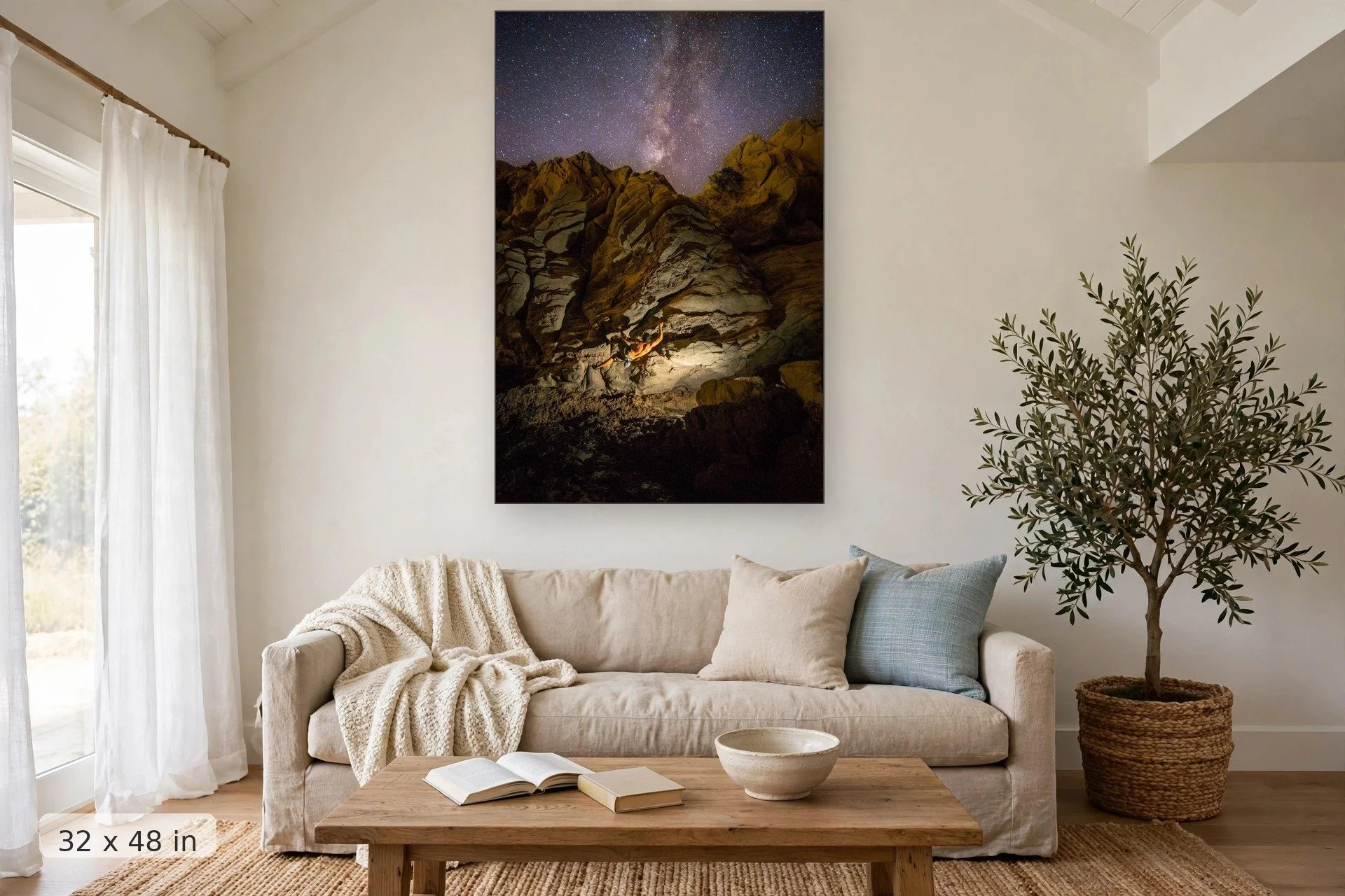 climber bouldering at night under the milky way — Climbing to the Milky Way print, 32x48 mockup above a living room sofa