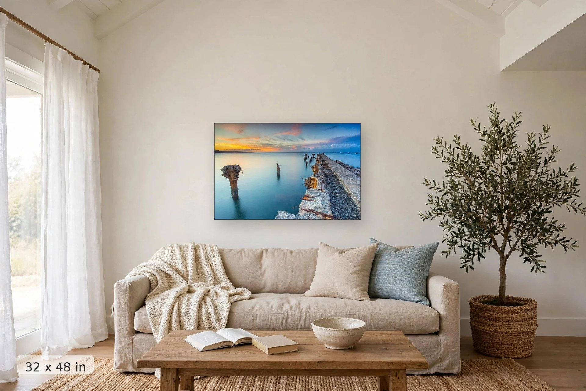 crumbling mala wharf looks out over serene blue water to orange sunset — Mala Remains print, 32x48 mockup above a living room sofa