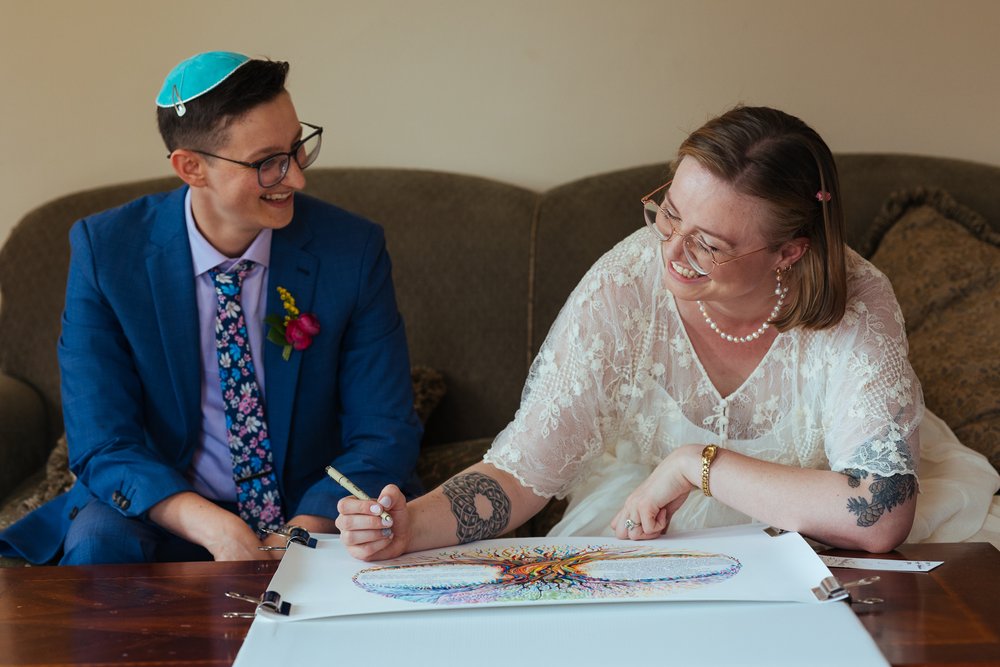  queer and nonbinary wedding couple signing ketubah at Endicott Estate in Massachusetts  