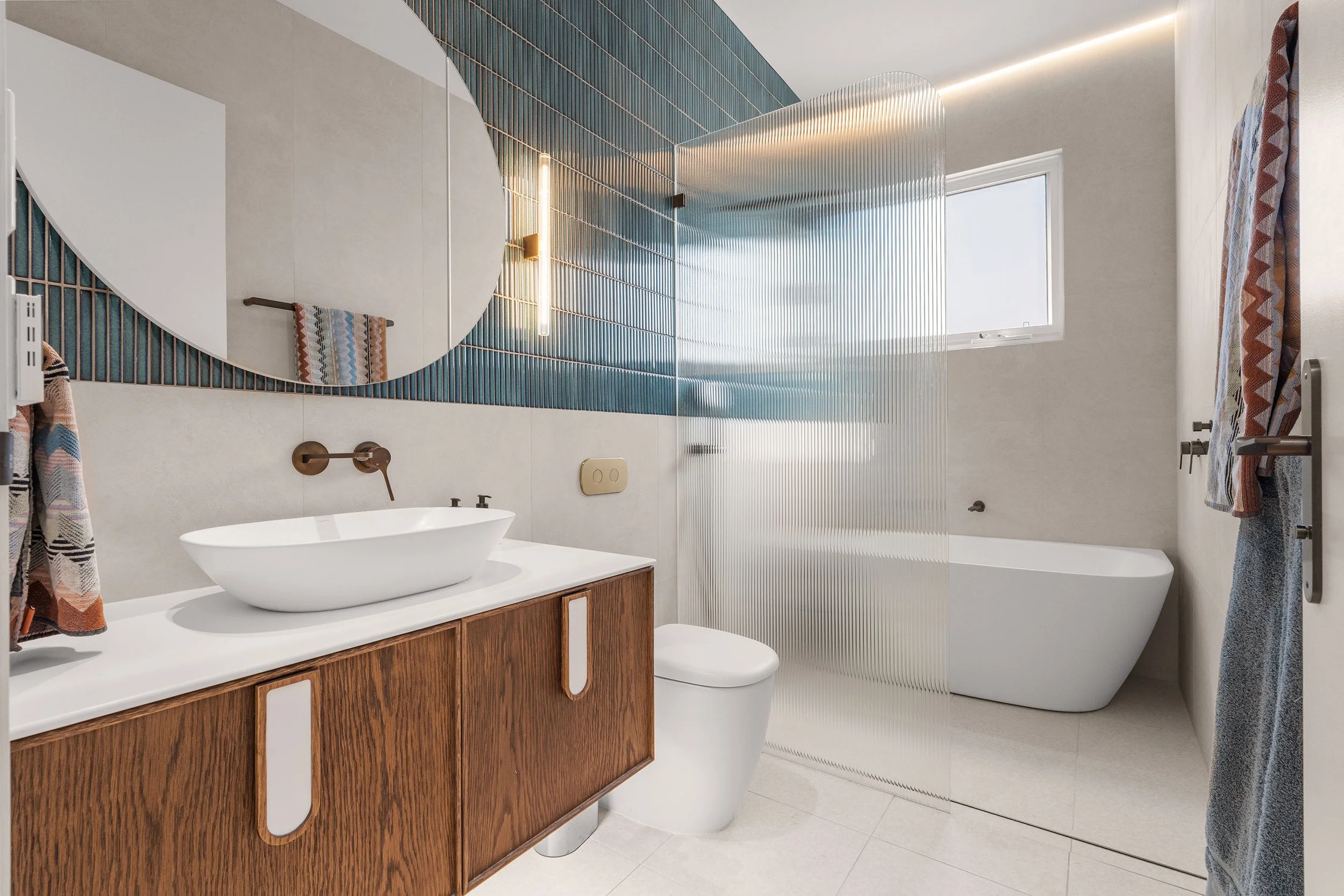 Curved forms, fluted glass and rich blue tiles give this bathroom its own personality while continuing the home's Art Deco influence.