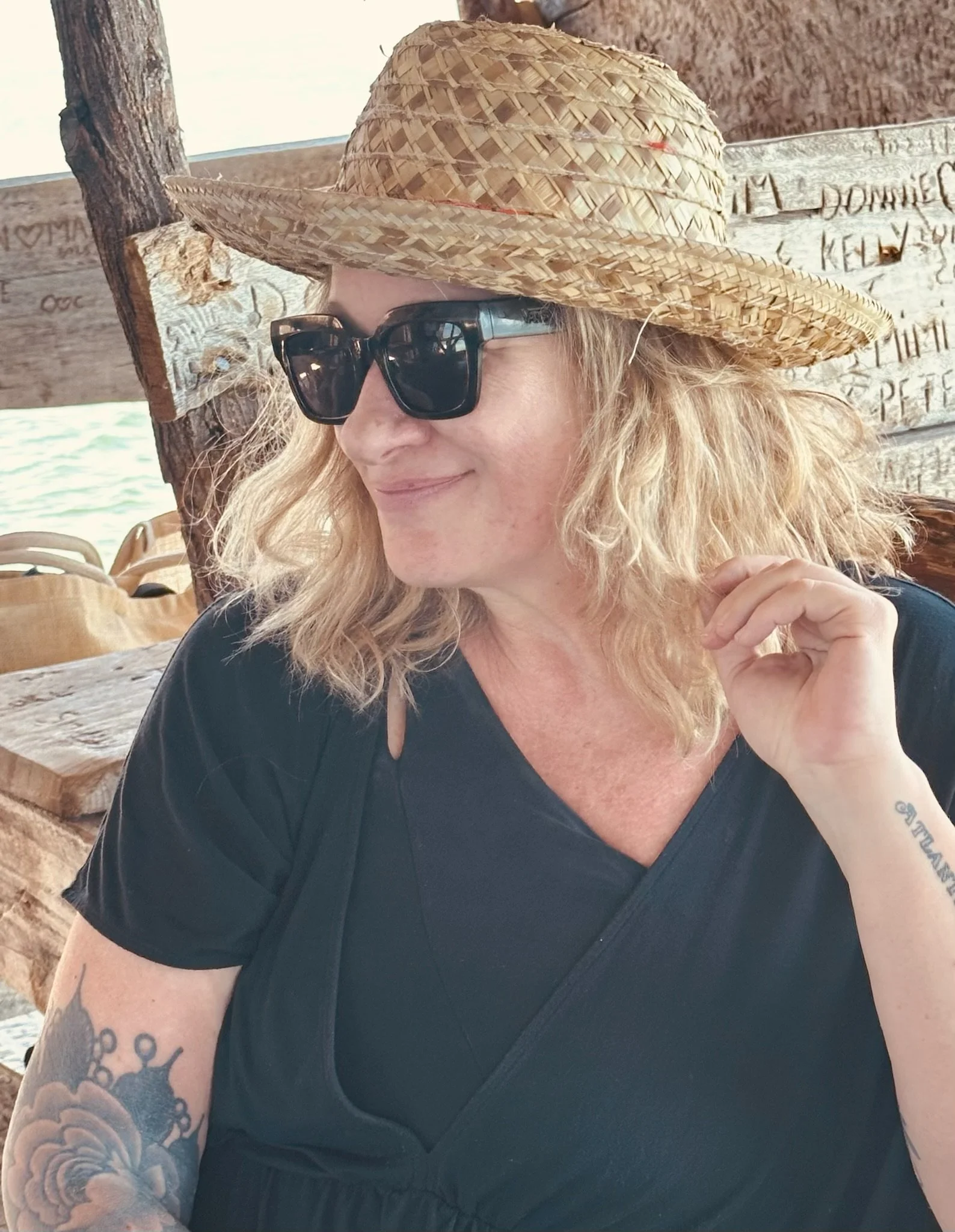 Lib Aubuchon, email strategist and copywriter, in a hat and sunglasses, smiling at an outdoor beach bar