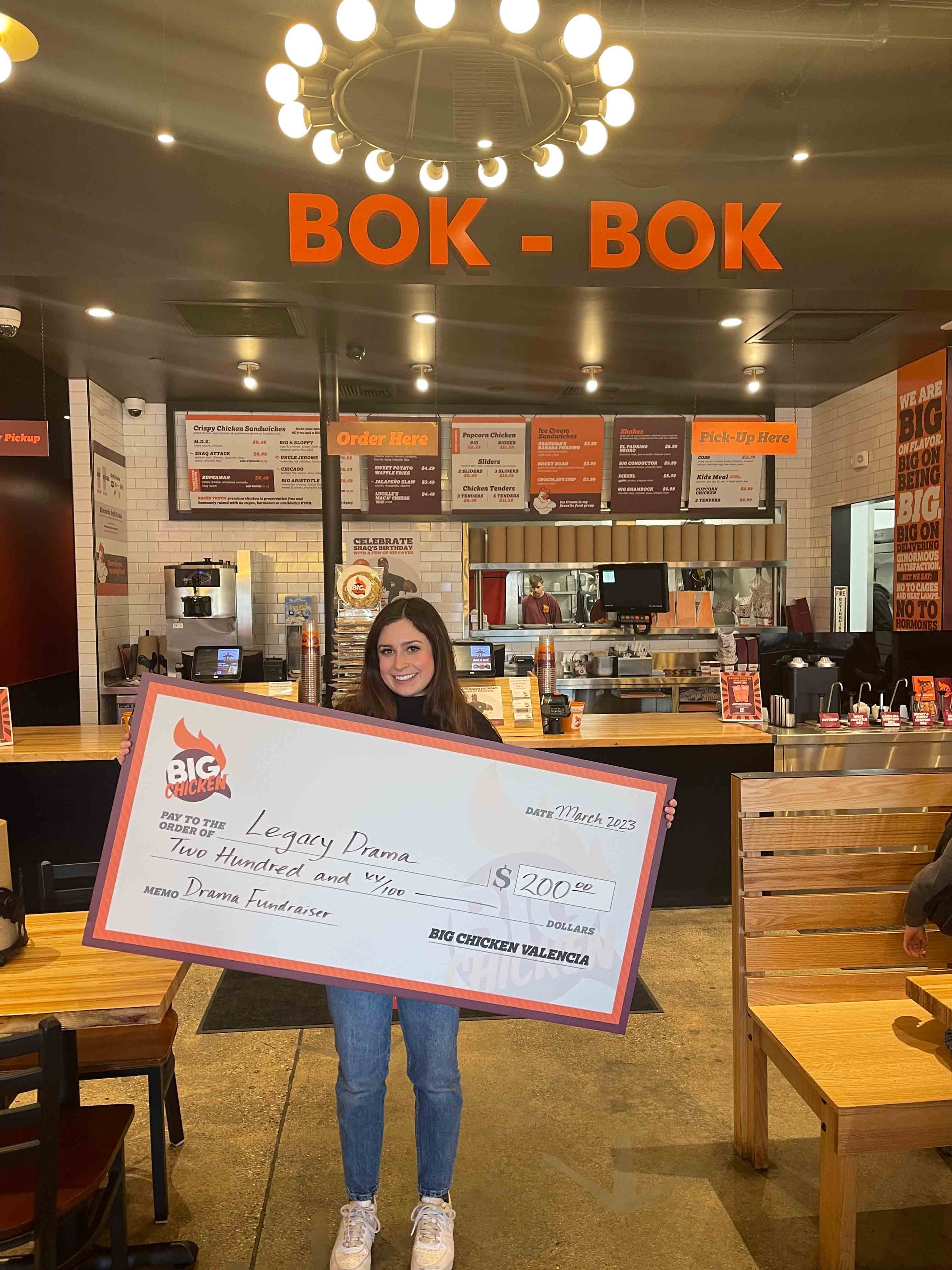 Legacy Drama student posing with oversized check donation