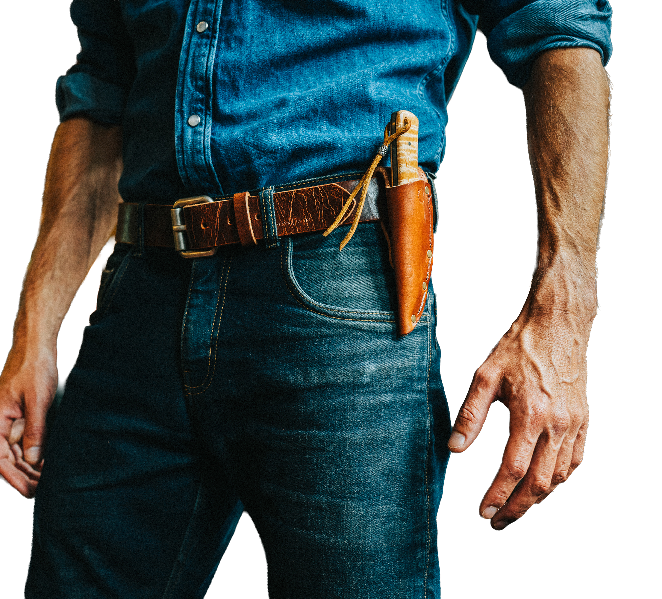 Man wearing a blue denim shirt with rolled-up sleeves and dark blue jeans. He has a brown leather belt with tools, including a leather pouch and a knife in a sheath, attached to it.