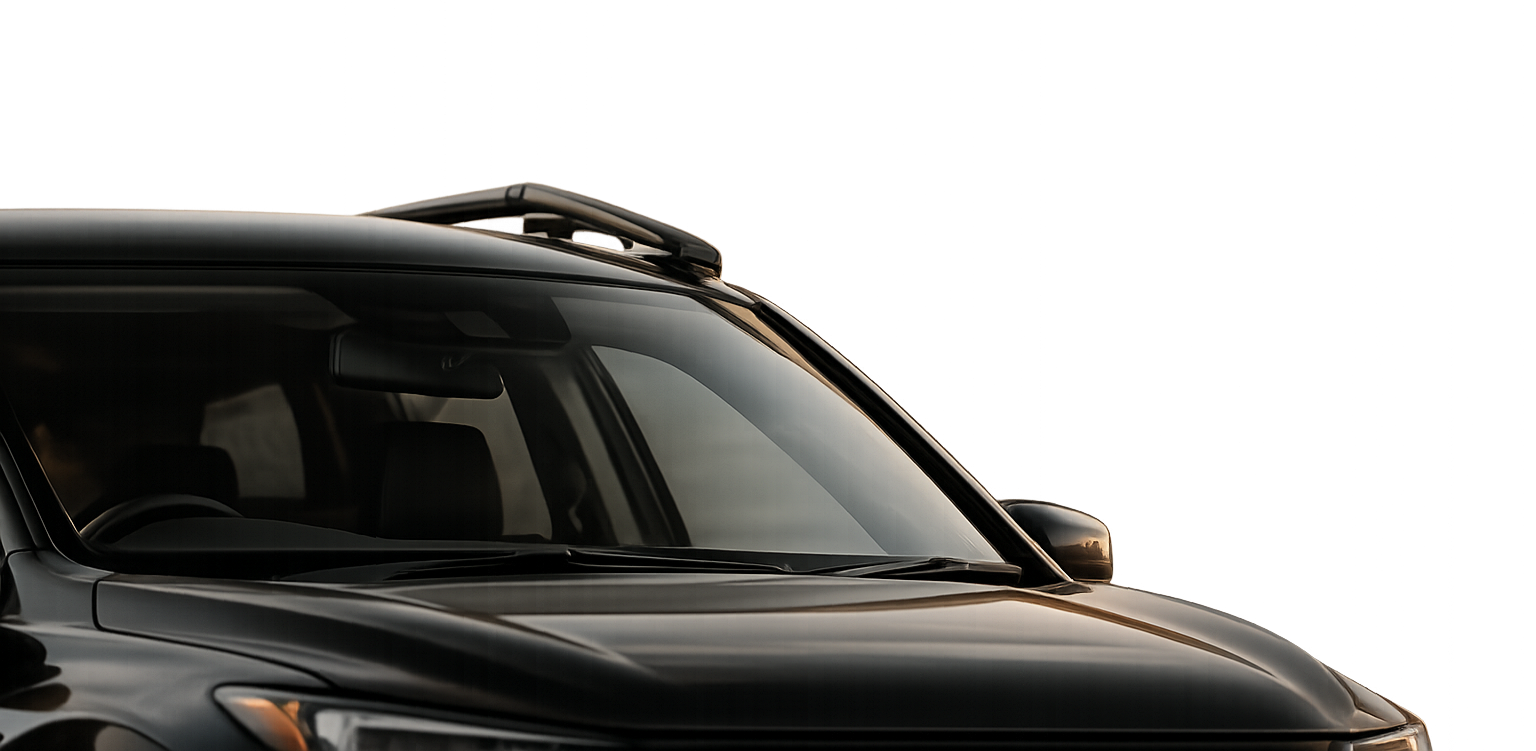 Close-up of a black car showing the windshield, hood, and side mirror, with a roof rack on top.