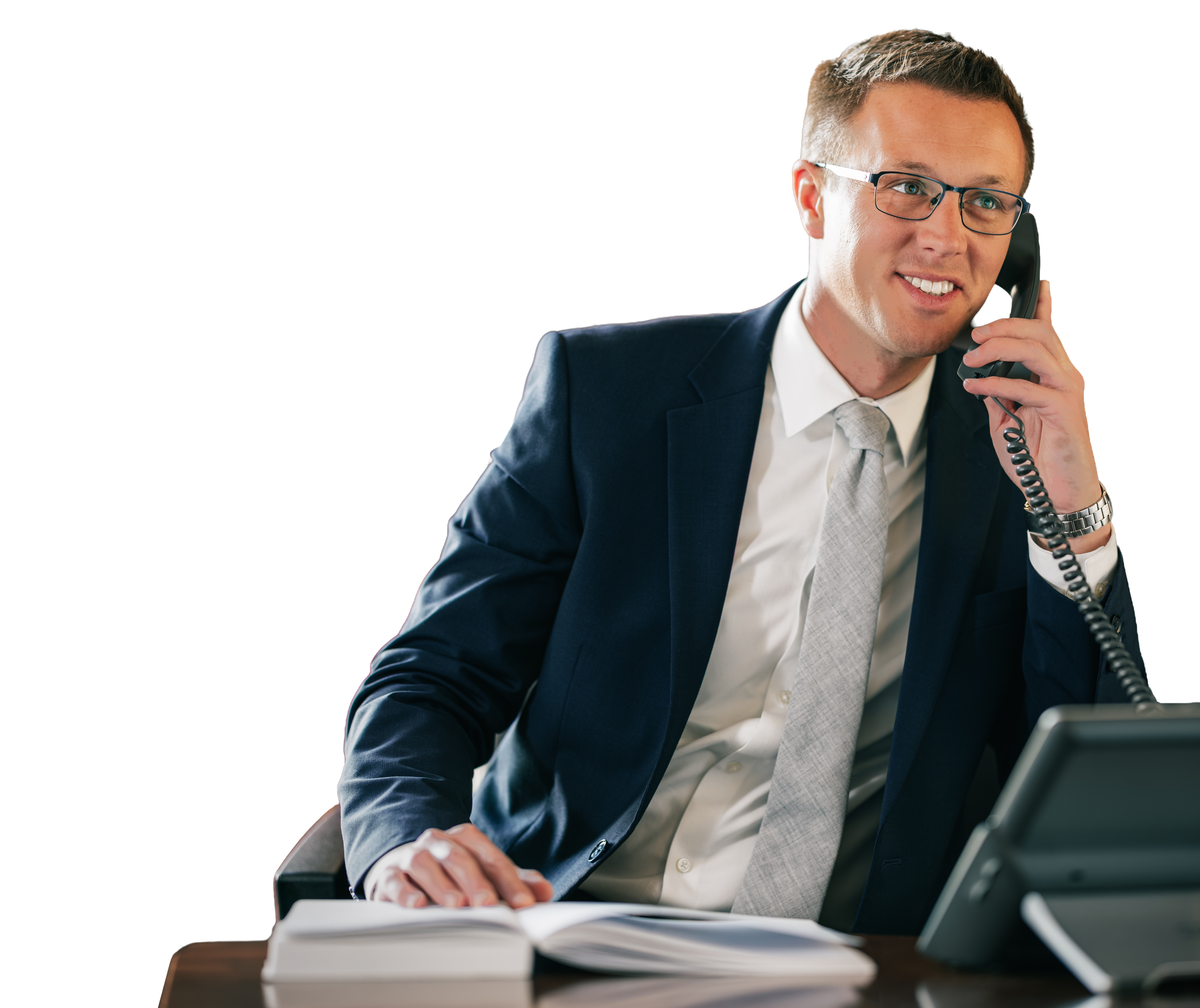 Man in suit and glasses talking on a landline phone in an office