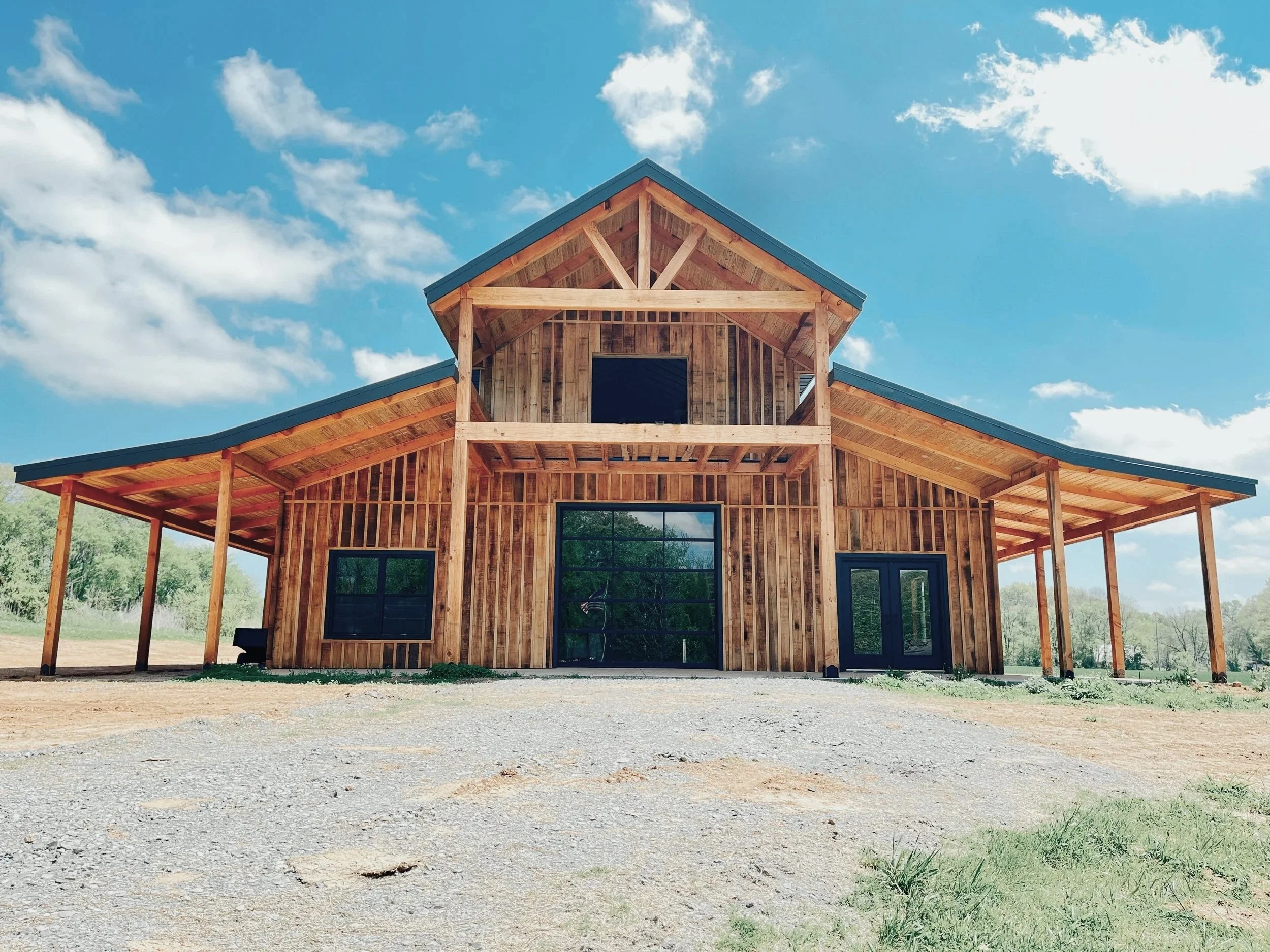 A wooden barn under construction with a blue sky and scattered clouds in the background.