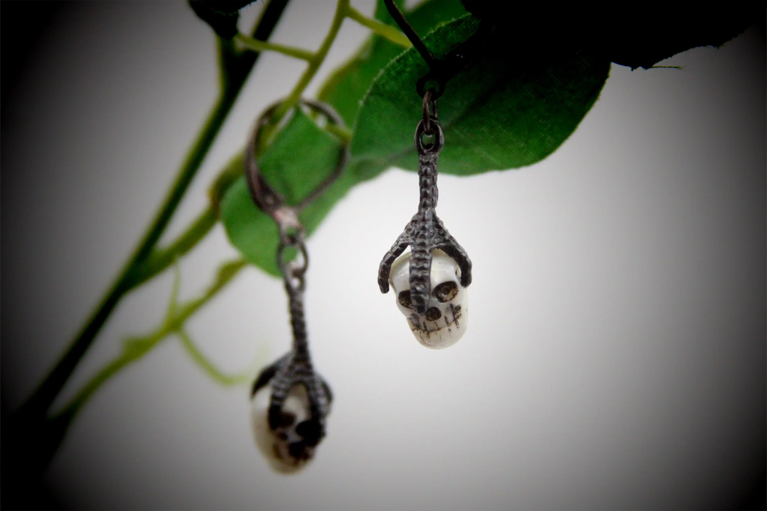Sterling silver raven claw earrings with carved skull beads