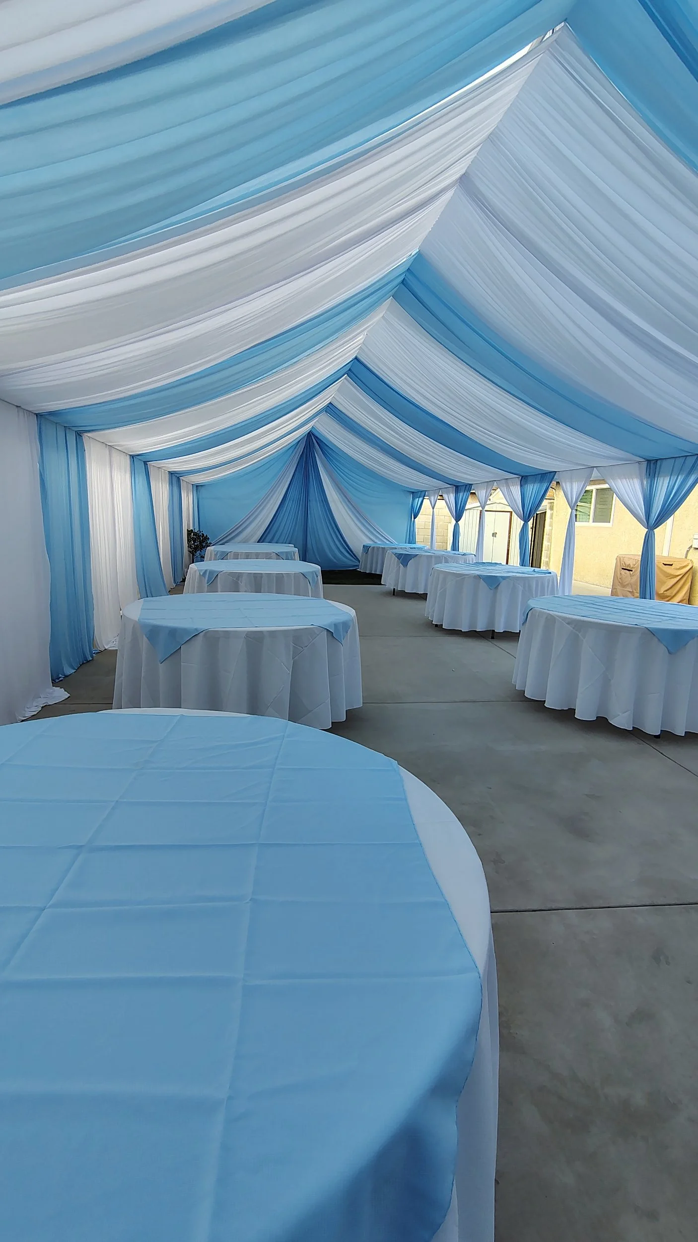 A decorated event tent with blue and white drapery on the ceiling and walls,