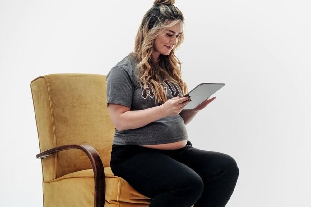 Pregnant woman on chair looking at iPad