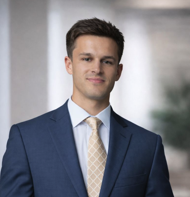 Person wearing a suit and tie indoors, with a decorative wall background.