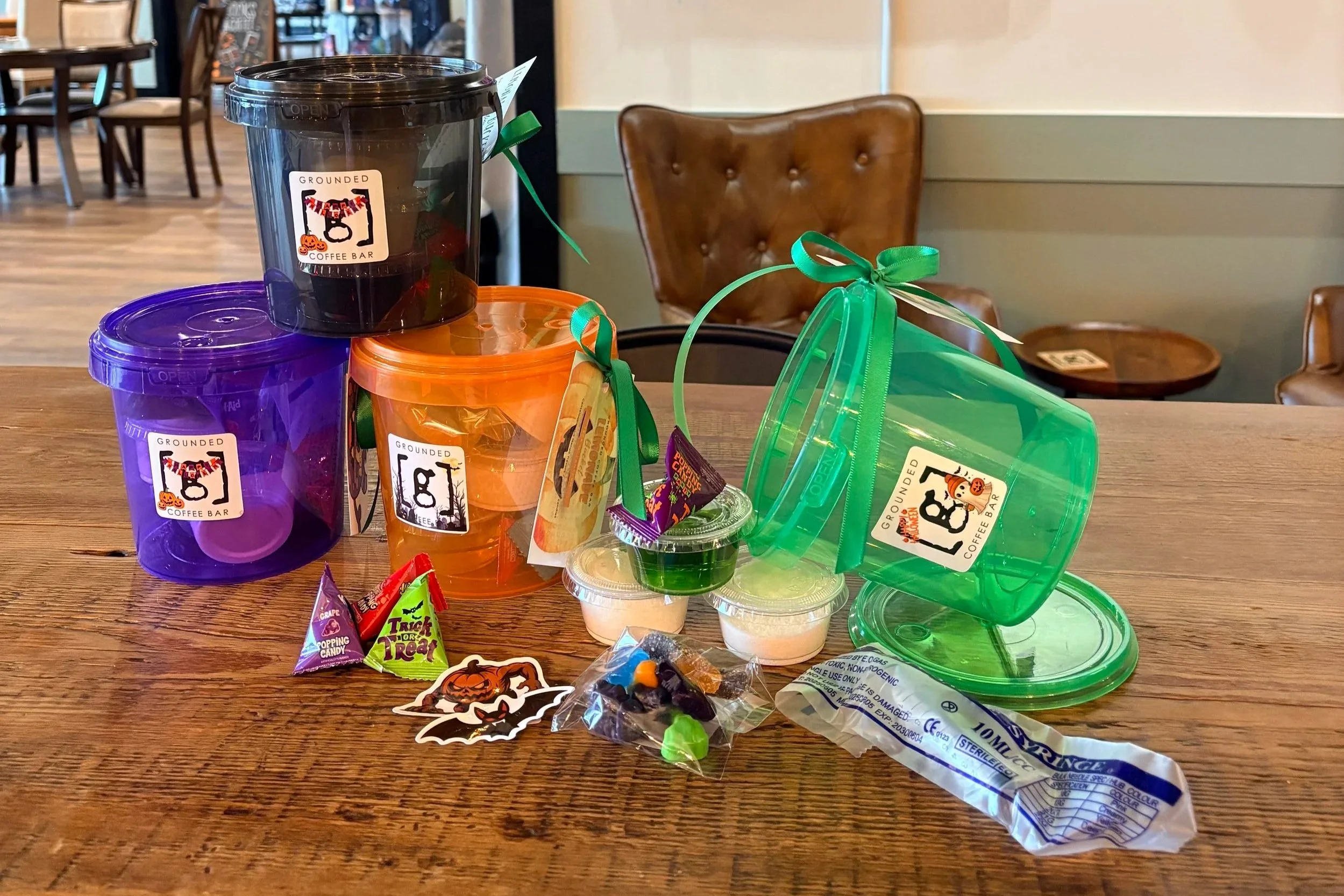 four plastic buckets on a table with lemonade, candies, and stickers.