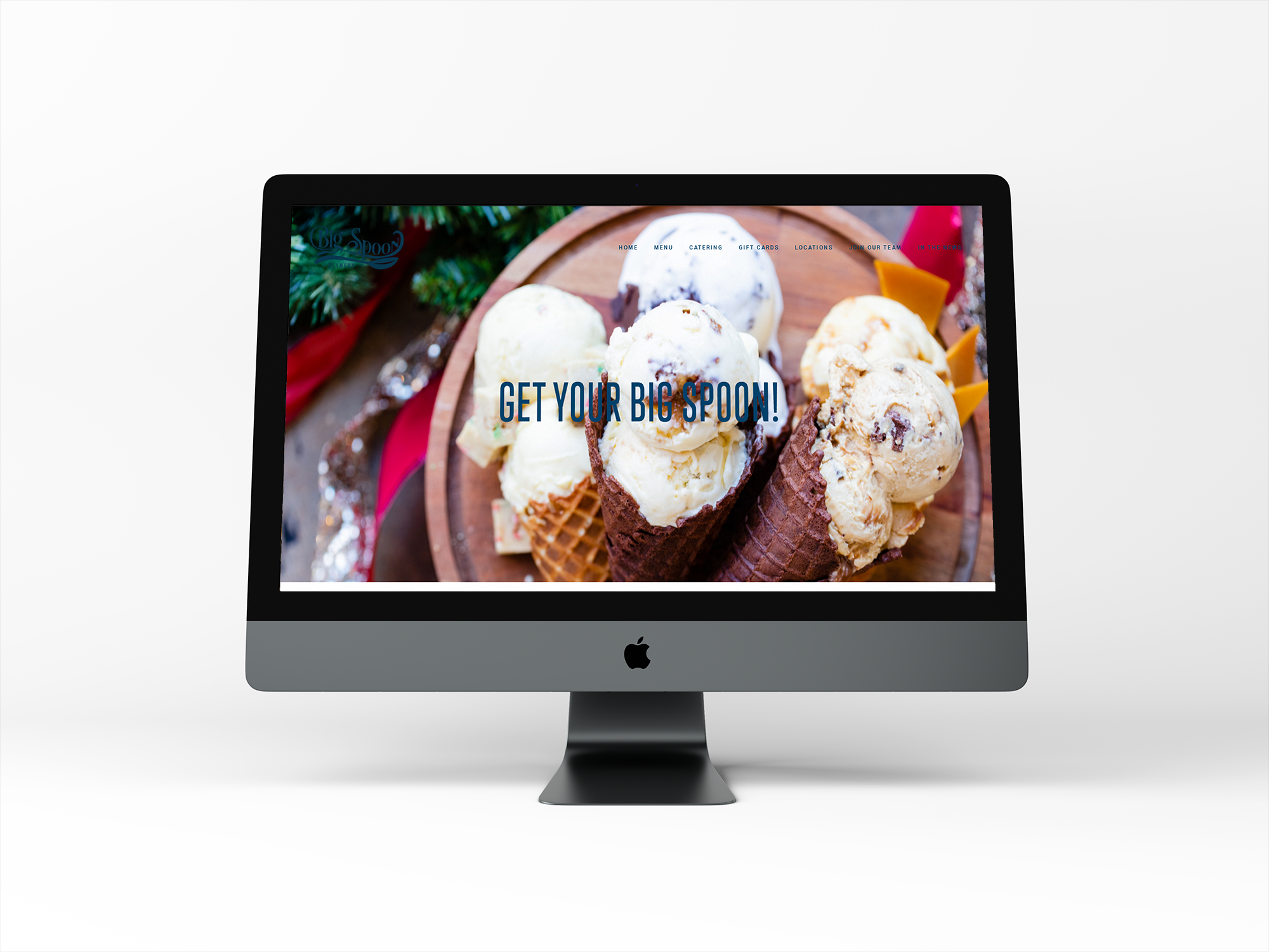 Computer monitor displaying a website for an ice cream shop with a background of various ice cream cones and the text 'Get Your Big Spoon!'