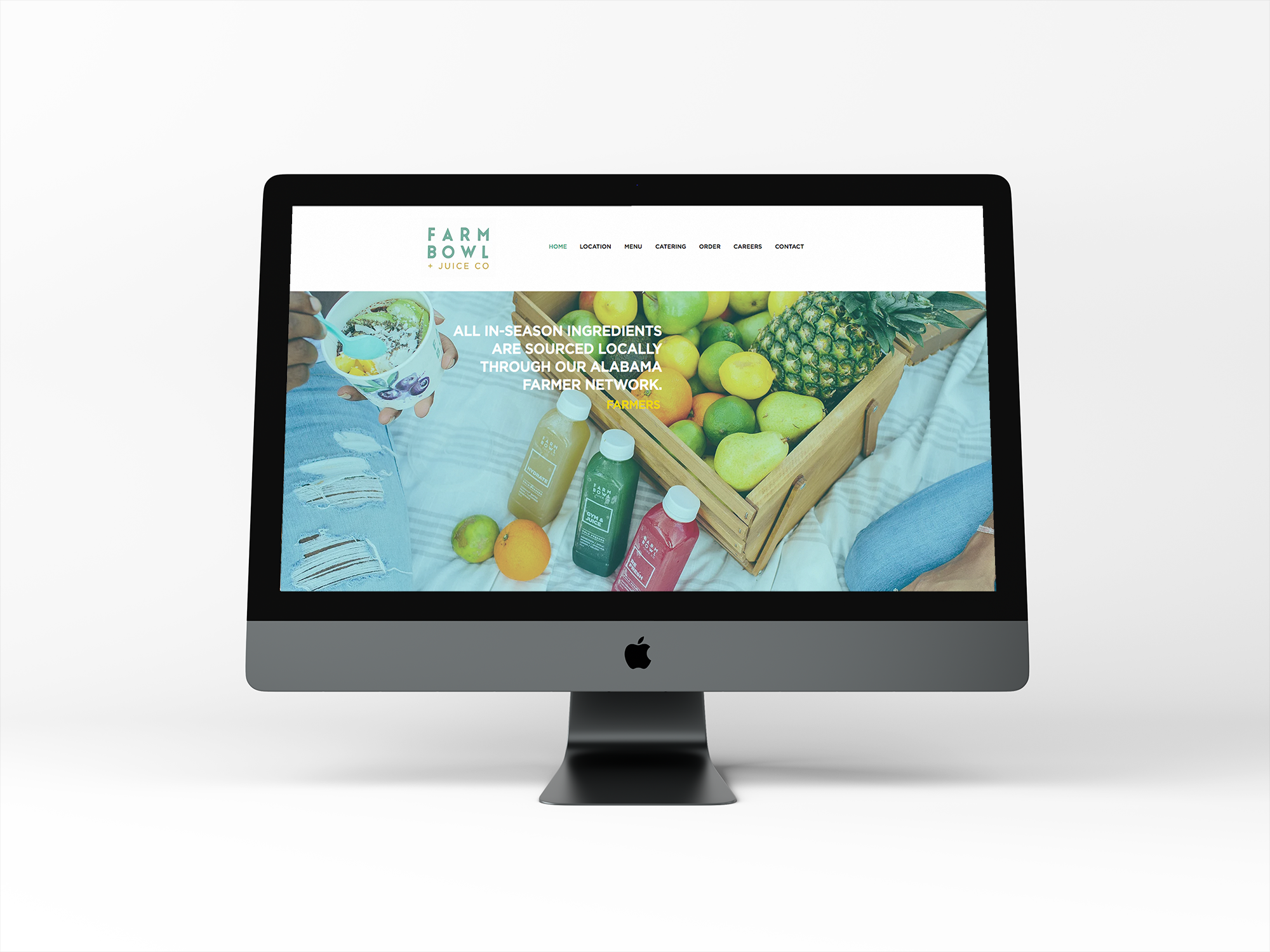 Computer monitor displaying a website for Farm Bowl + Juice Co, featuring fresh fruits and vegetables, juice bottles, and a person pouring a smoothie or juice.