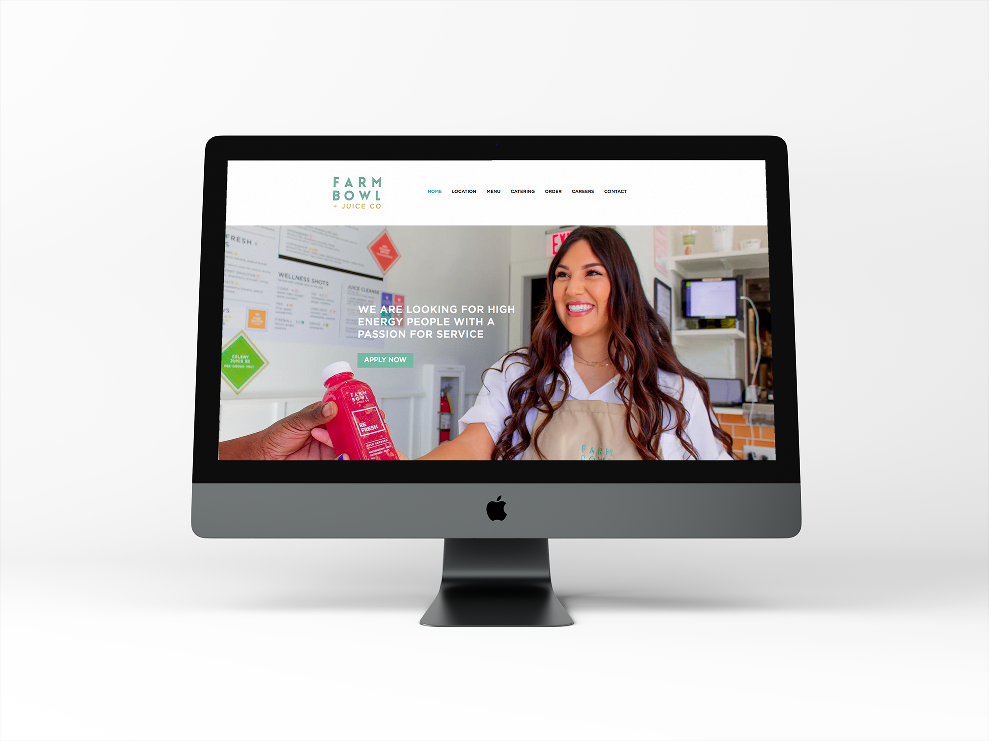 Computer monitor displaying the homepage of Farm Bowl + Juice Co with a smiling woman in a white apron serving a colorful drink.