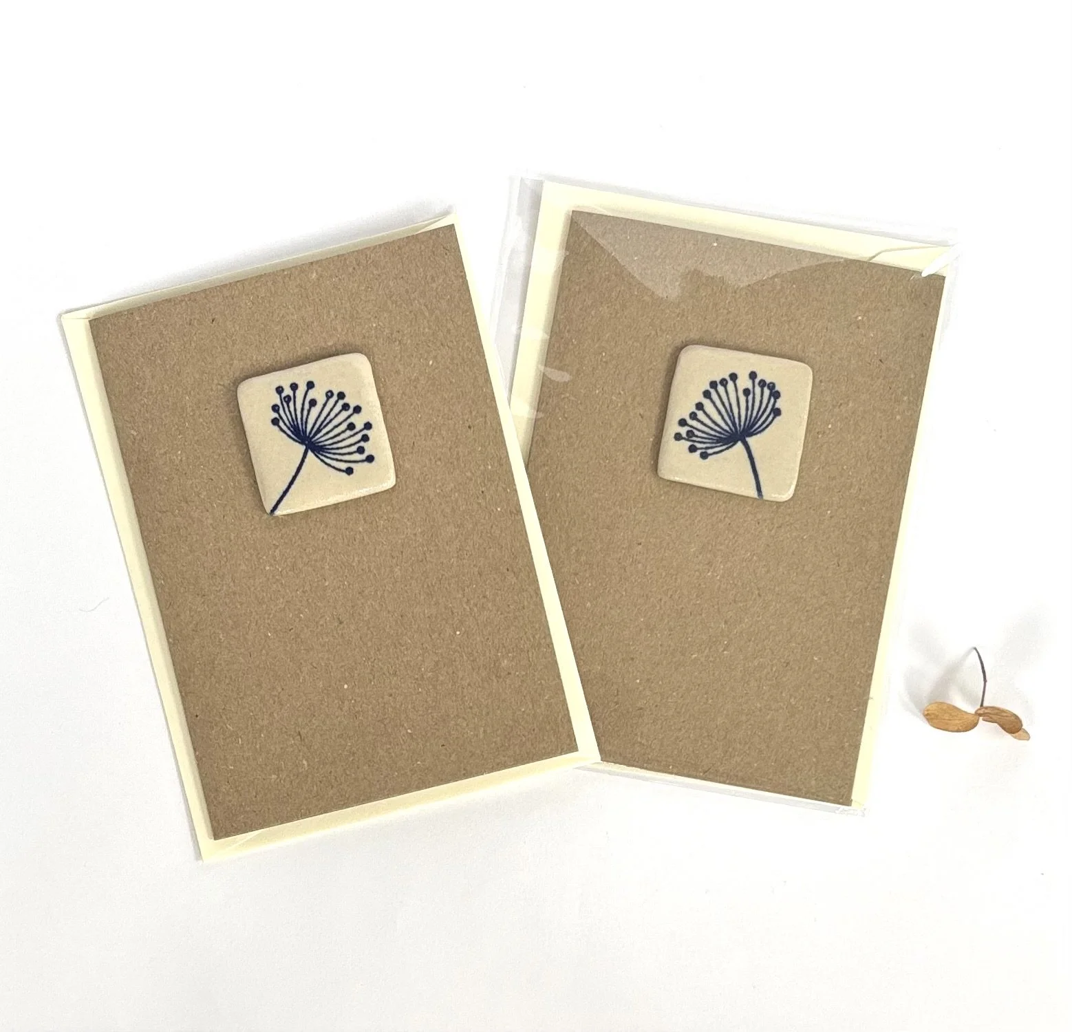 Two cards, each featuring a ceramic tile with a black flower design.