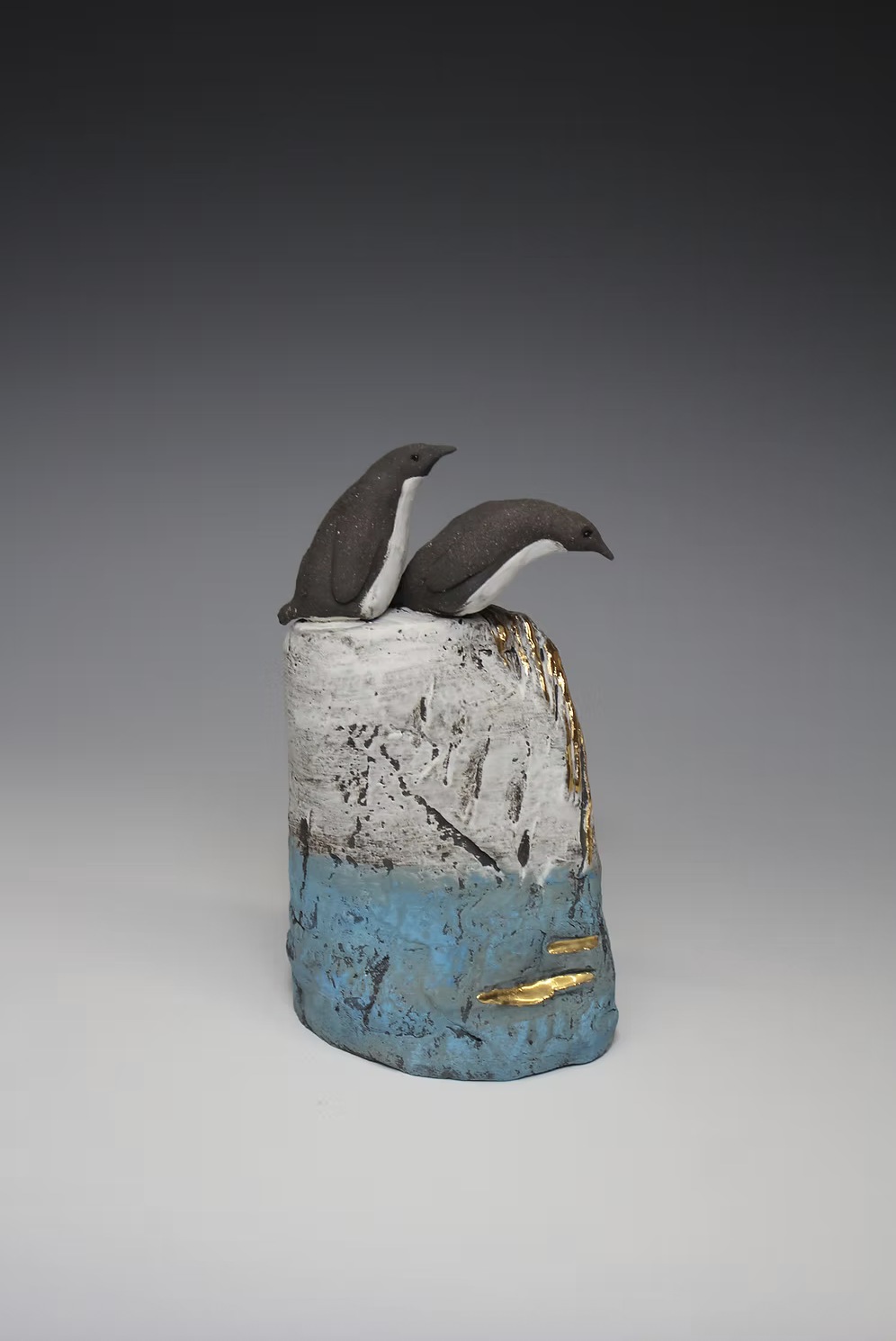 An original hand built ceramic sculpture by British ceramicist Jack Durling showing two penguins contemplating diving into the ocean.