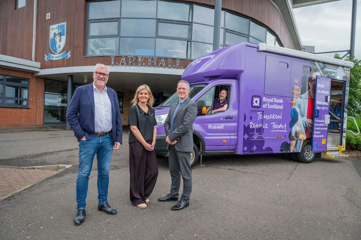 Representatives from Scottish Financial Enterprise, Royal Bank of Scotland and Larkhall Academy standing beside the Royal Bank of Scotland Bank on Wheels mobile branch outside Larkhall Academy as part of the Schools Banking Pilot.