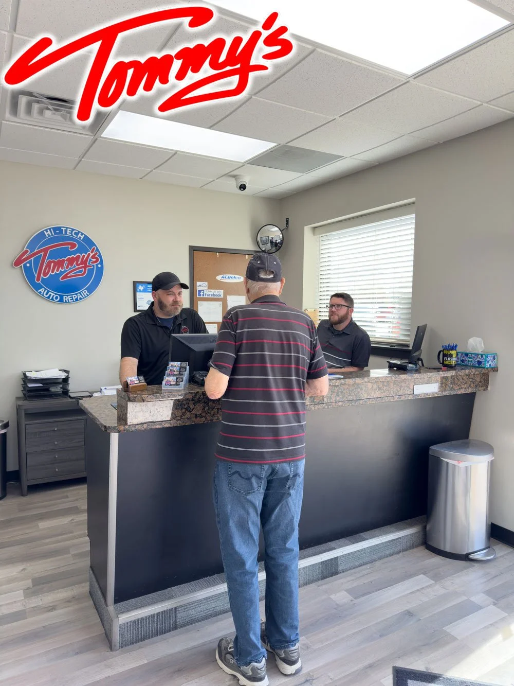Customer standing at the counter talking to two employees at Tommy's Auto Repair shop