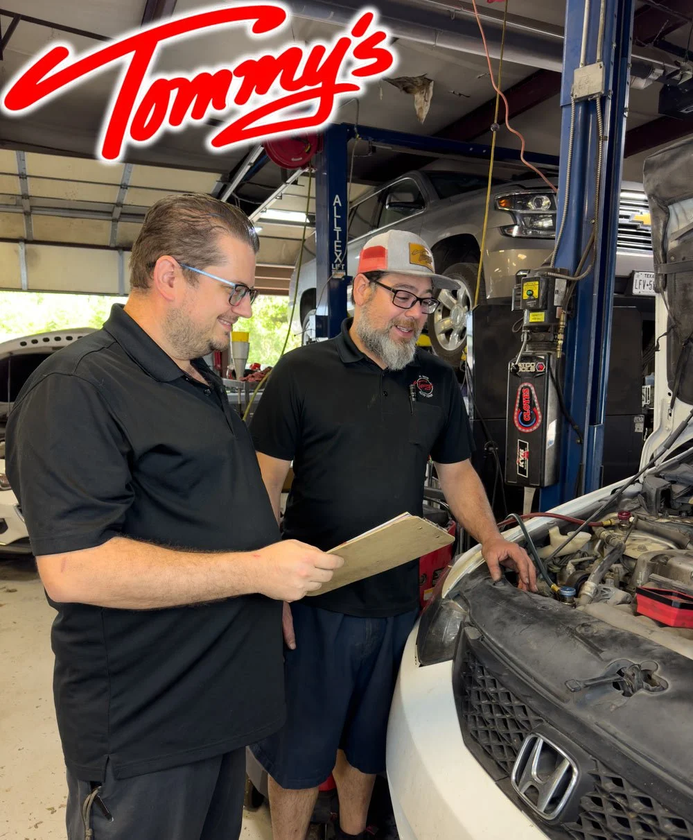 Two men working on a car engine in an auto repair shop.