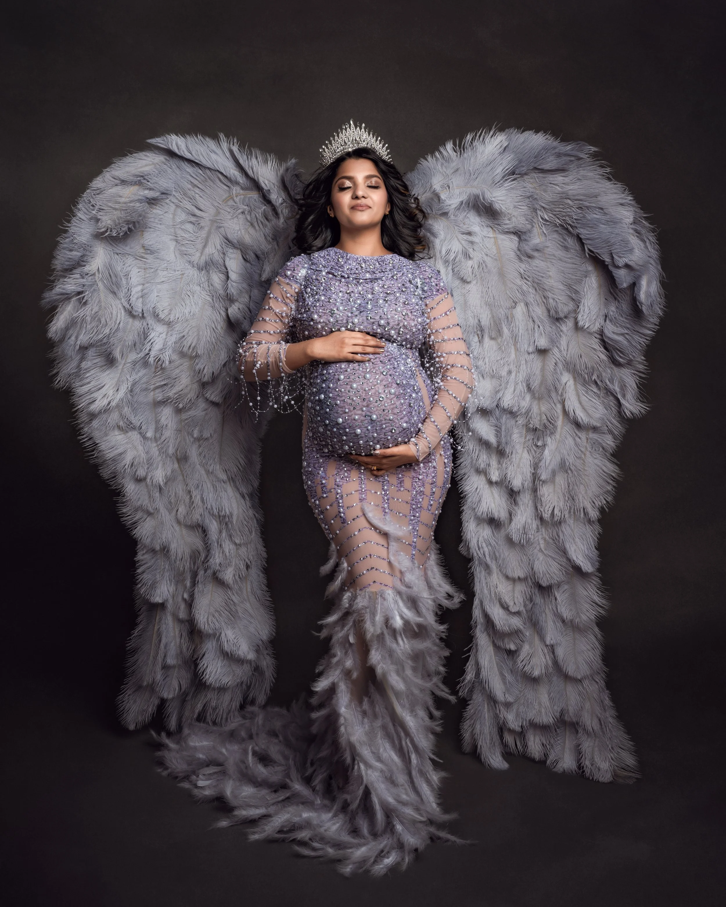 A beautiful pregnant woman dressed in grey with beautiful wings