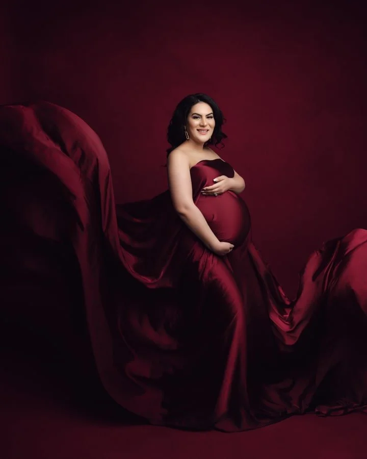 Maternity portrait of a glowing mom in burgundy dress with burgundy background
