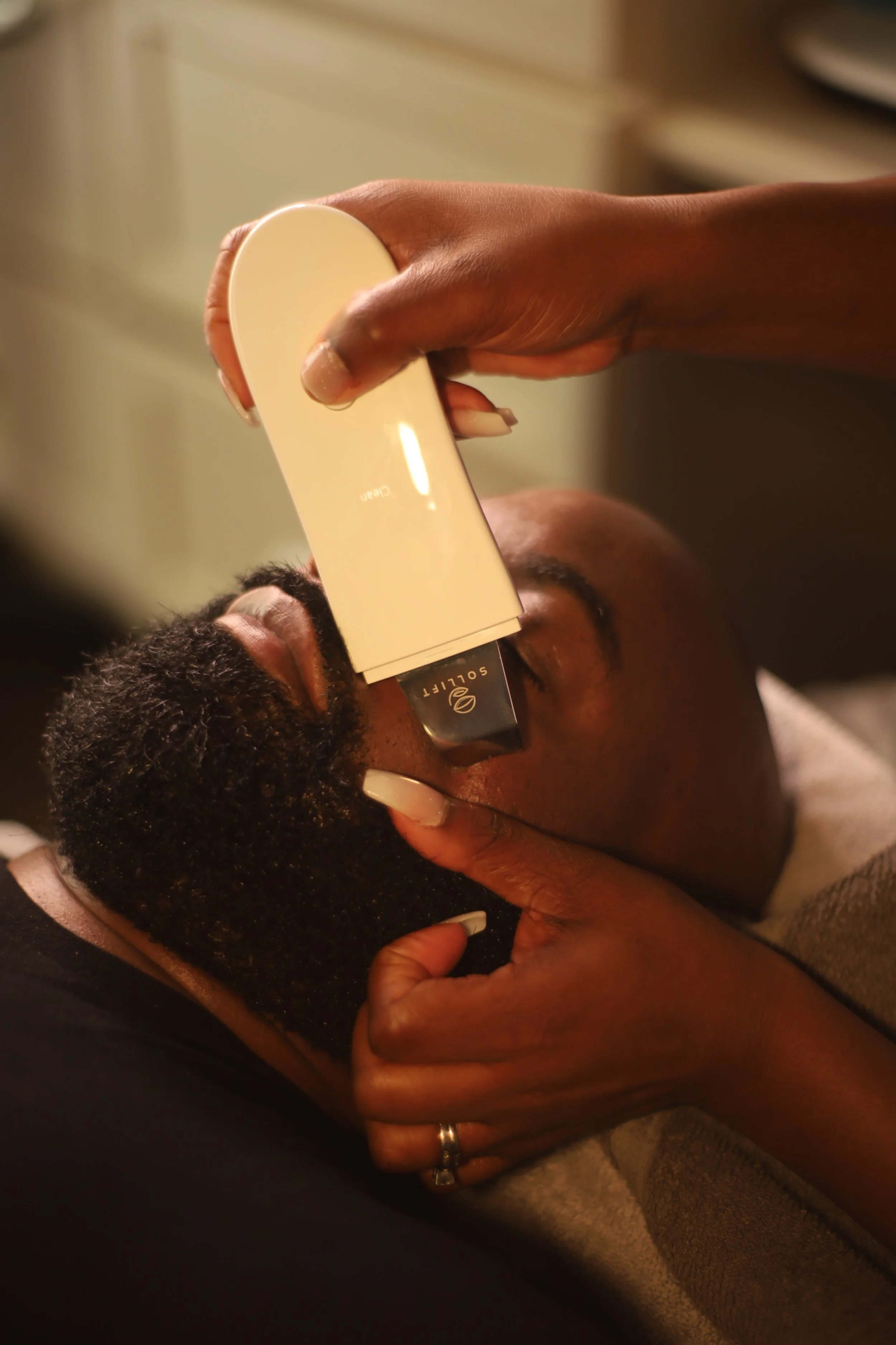 Person receiving a facial treatment with a device at a spa or skincare clinic.