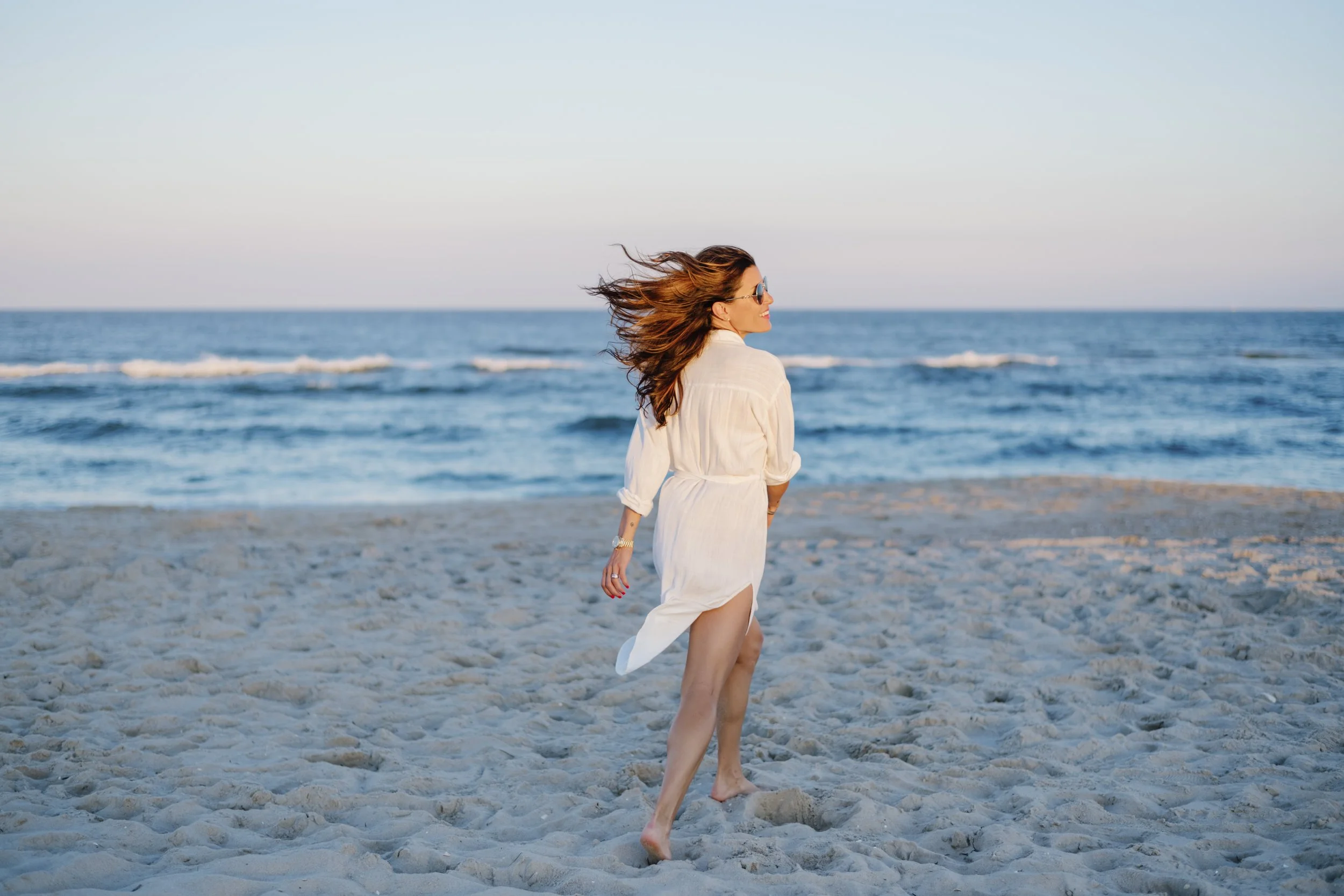Cheslea in suglasses and white dress on beach