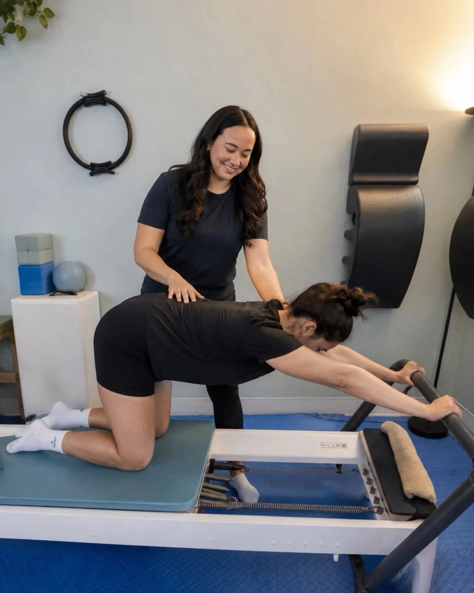 A woman doing Pilates on a mat, lying on her back and holding a magic circle over her chest.