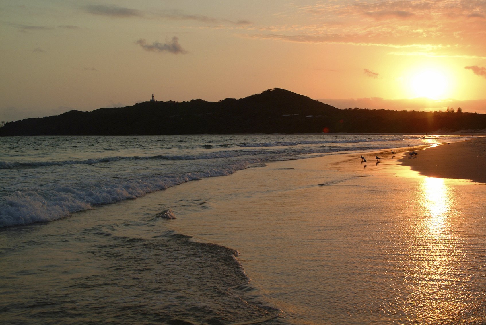 View at sunrise from Main Beach Byron Bay looking south towards the Pass and Cape Byron Headland and the Byron Lighthouse