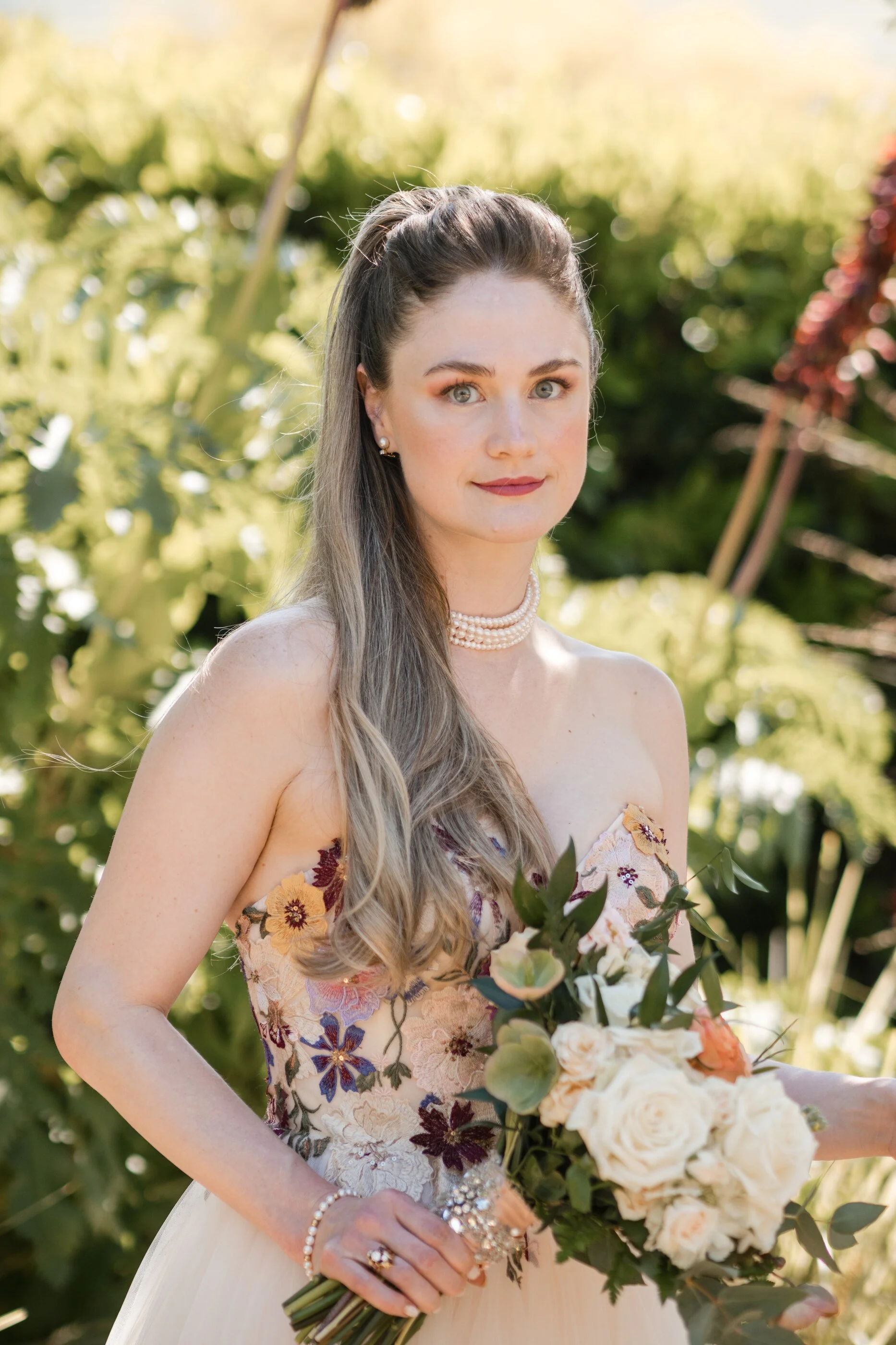 Romantic garden bridal makeup with soft peach eyeshadow, glowing, natural skin, and elegant bridal portrait, holding bouquet. Floral embroidered wedding dress pearl necklace. Bridal makeup for green eyes bridal makeup for soft autumn color analysis s