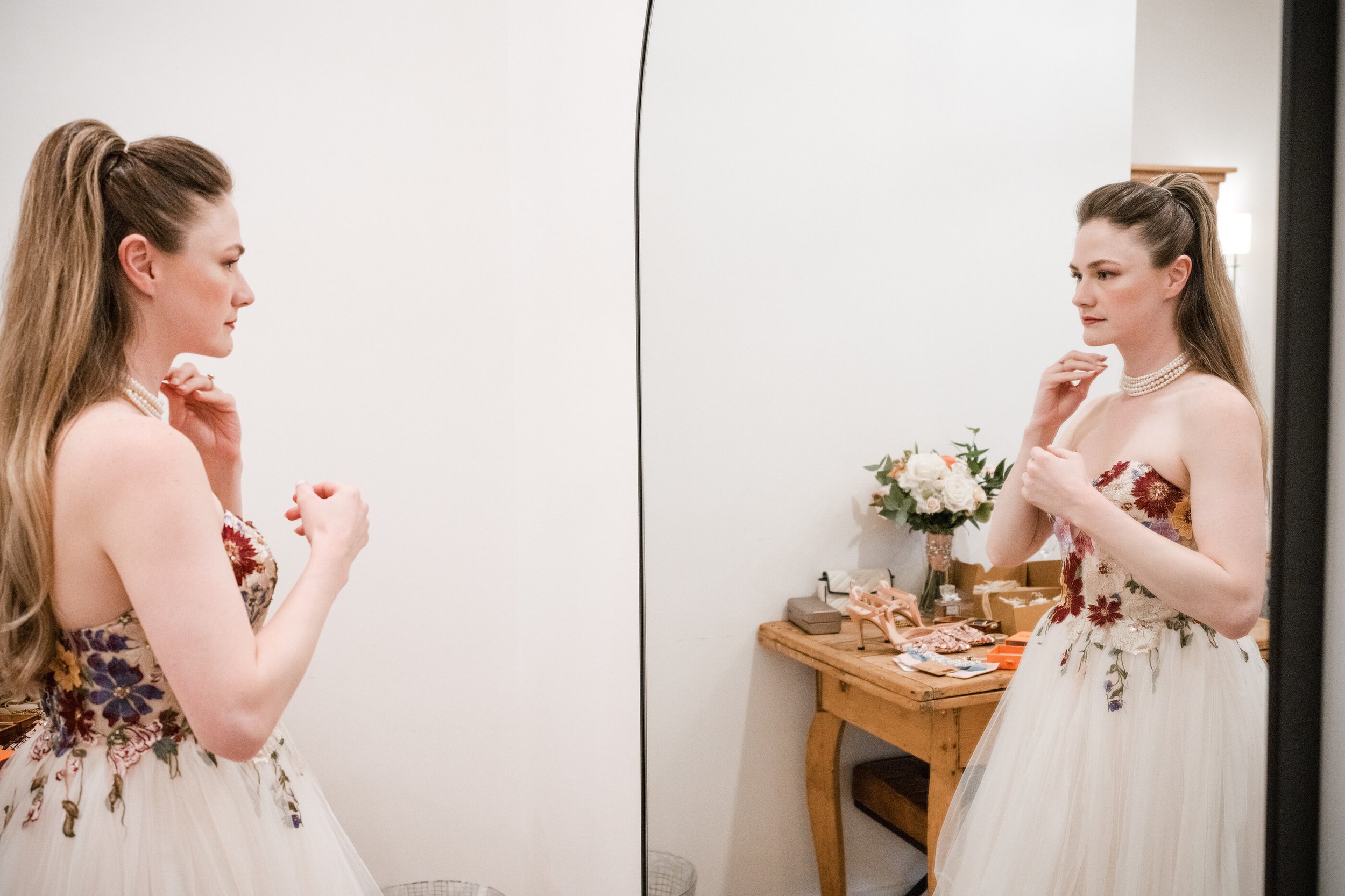 Bride checking her finished wedding hair and natural bridal make up in the mirror before the ceremony. Bride admiring her completed wedding hair and makeup before the ceremony. Final bridal hair and makeup look. Bridal color analysis soft Autumn make