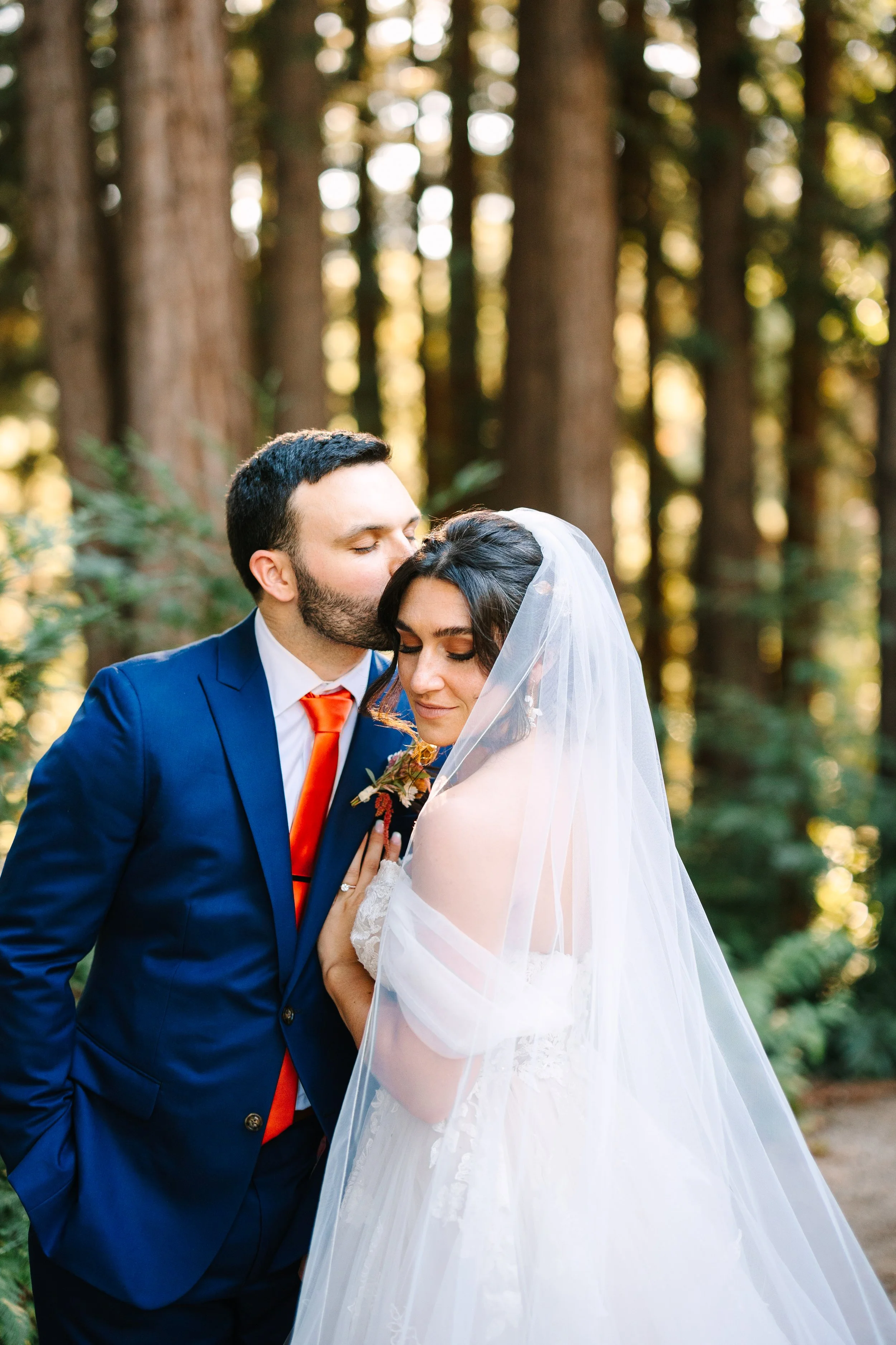 Natural glam, bridal hair and makeup with romantic updo and veil at a redwood forest wedding. Groom, kisses, bride, romantic wedding photos, northern California Santa Cruz mountains Beauty by Santi 