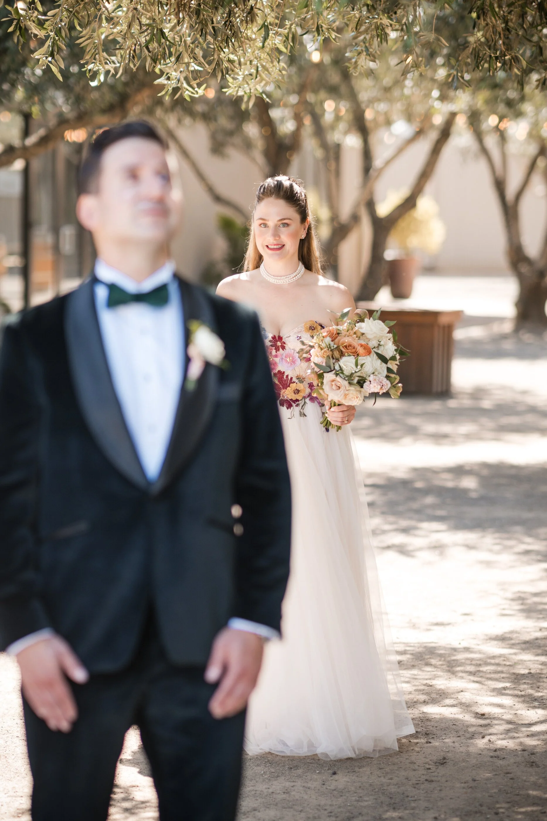 Romantic garden wedding first look with bride, wearing soft glam bridal makeup and elegant half of bridal hairstyle bride approaches groom for a romantic, first look in a garden setting, showcasing, soft, glam bridal makeup, and a polished half of we