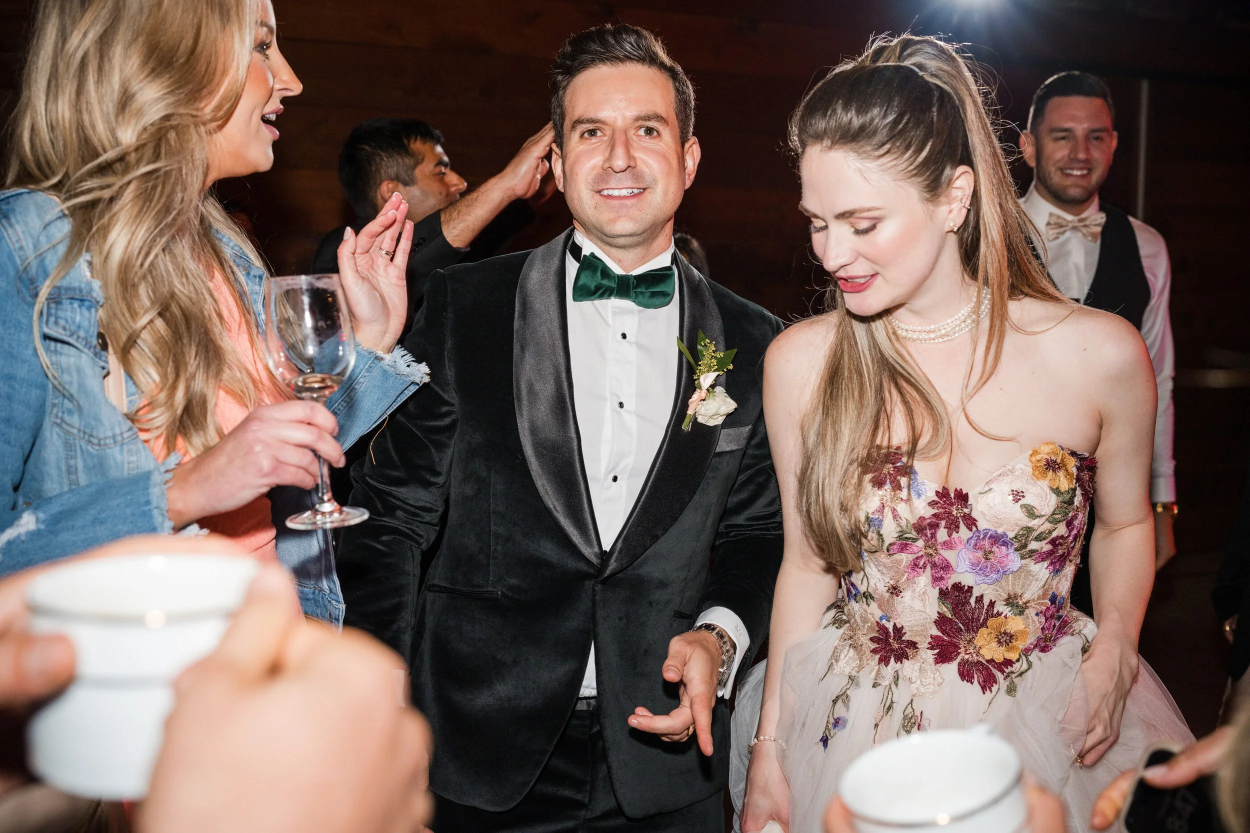 Bright dancing during wedding reception with guest while wearing soft glam bridal makeup with glowing skin, warm peach tones, and a romantic half a bridal hairstyle with soft waves that holds beautifully throughout the celebration. Bridal color analy