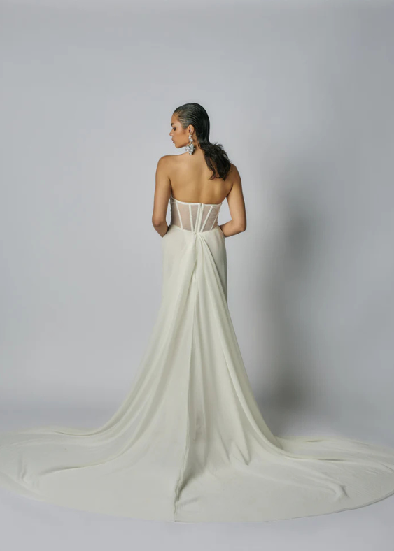 Picture of an organza wedding gown from behind with draped detail and sheer boned corset.  The Bride is facing forwards and the image is from behind with a neutral background.