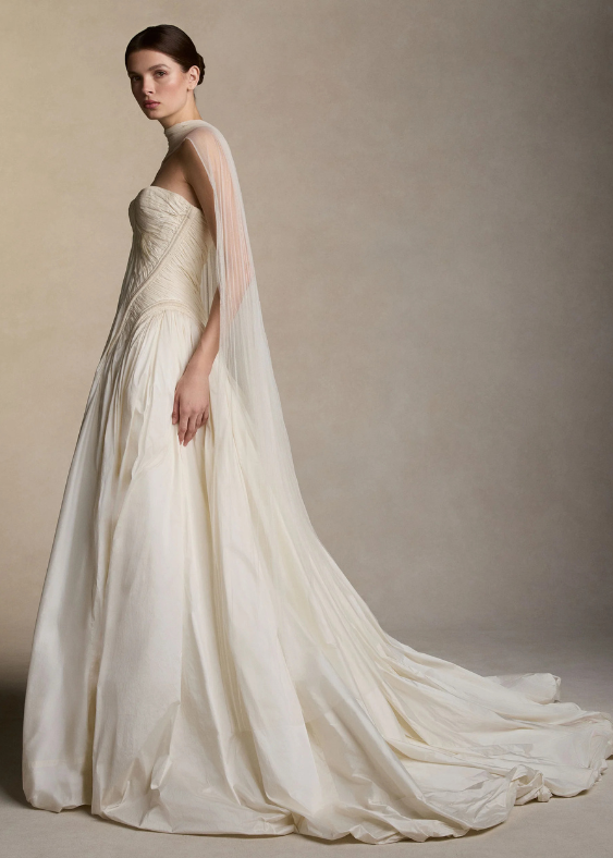 A woman seen from the side standing on a neutral background wearing a long, contemporary bridal scarf for a wedding in Australia.