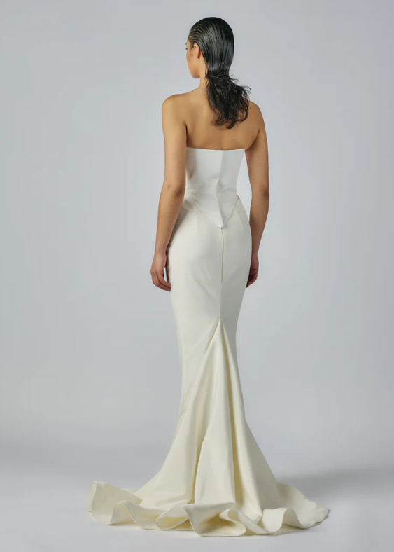 Details of a modern bridal skirt from the back with the bride standing on a white background