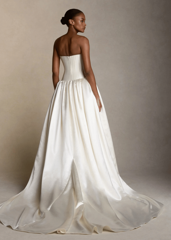 Back view of a woman standing in a Luxury Australian bridal gown with modern boned bustier and drop waist and gathered ball gown skirt.