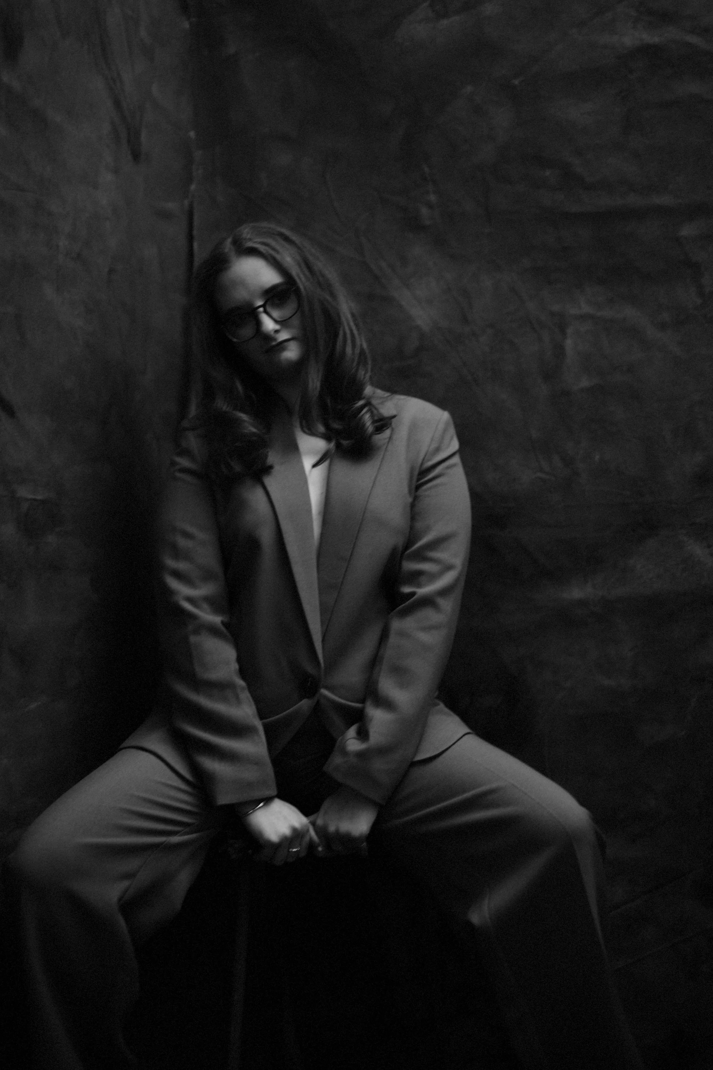 Black and white photo of a person in a suit sitting against a textured background.