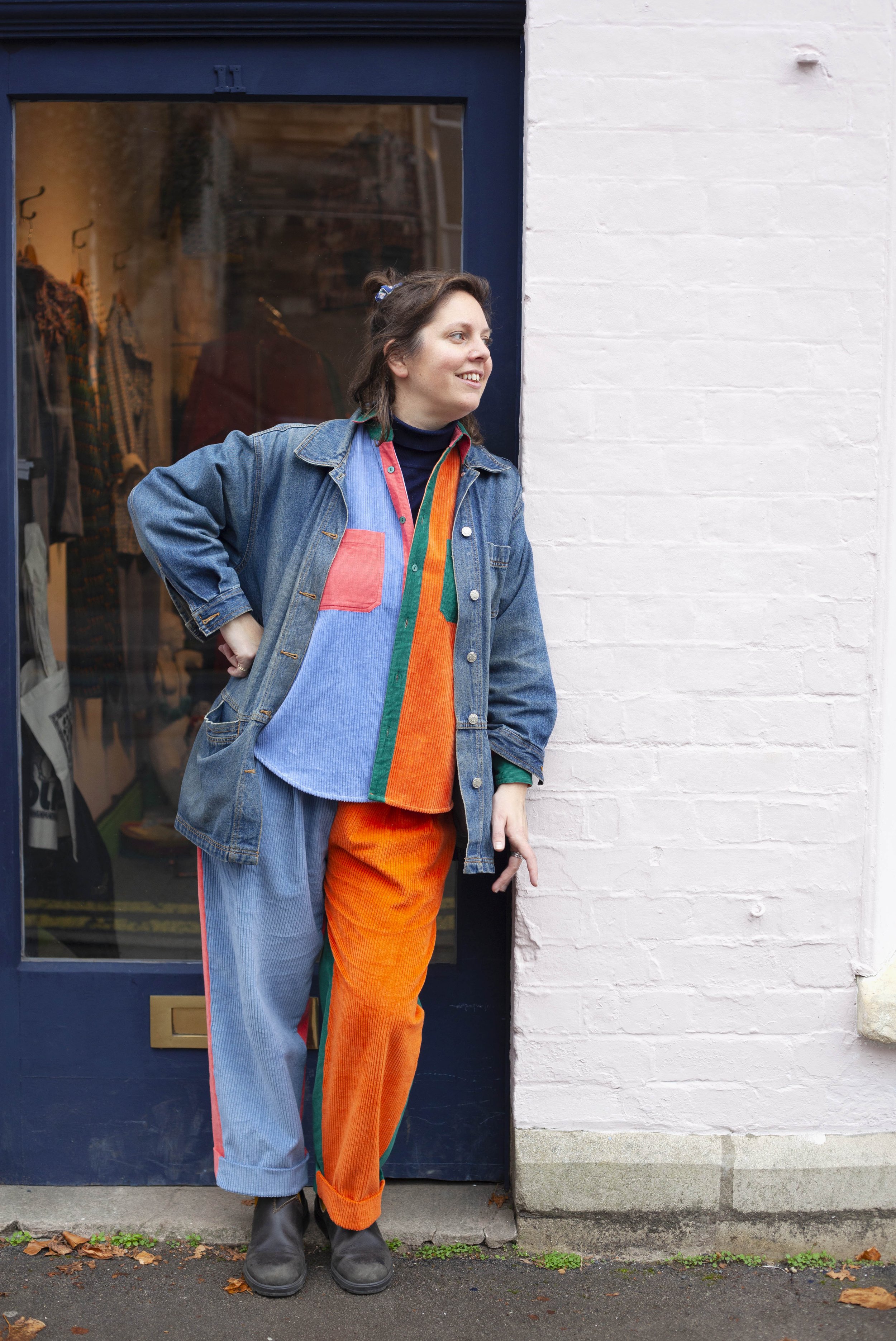 Portrait photograph of Alice Begg standing in the doorway of her Humphries and Begg shop in Stroud wearing bright colours