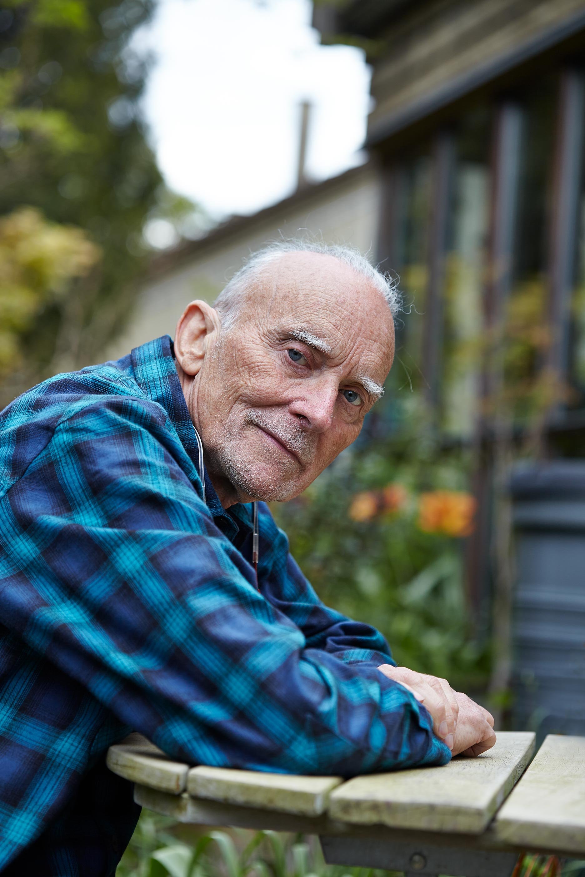 A portrait photograph of an old man sat at his garden table in Stroud