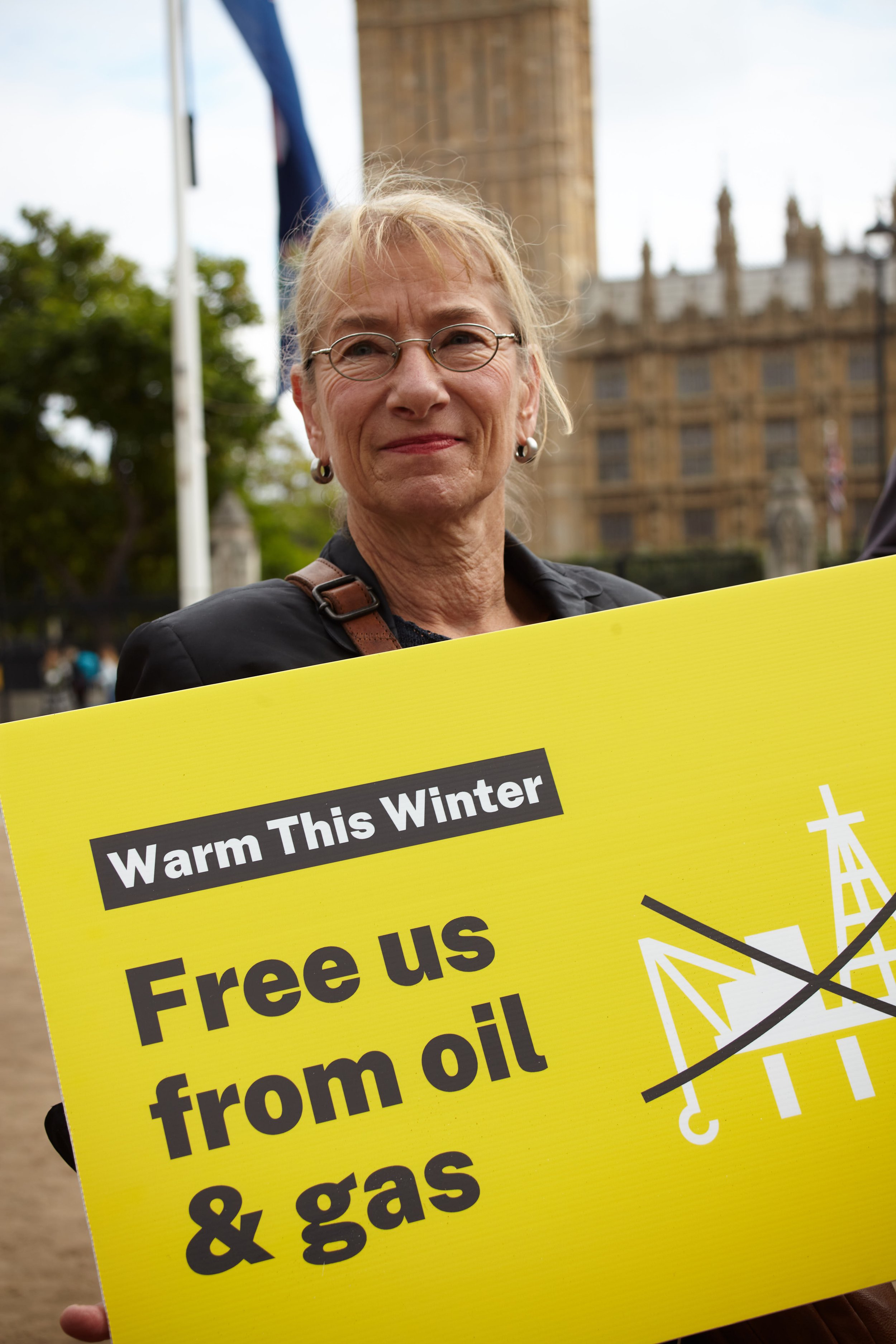 Portrait photograph by Hatty Frances Bell of a blonde woman holding a Warm This Winter placard at a political demonstration in London