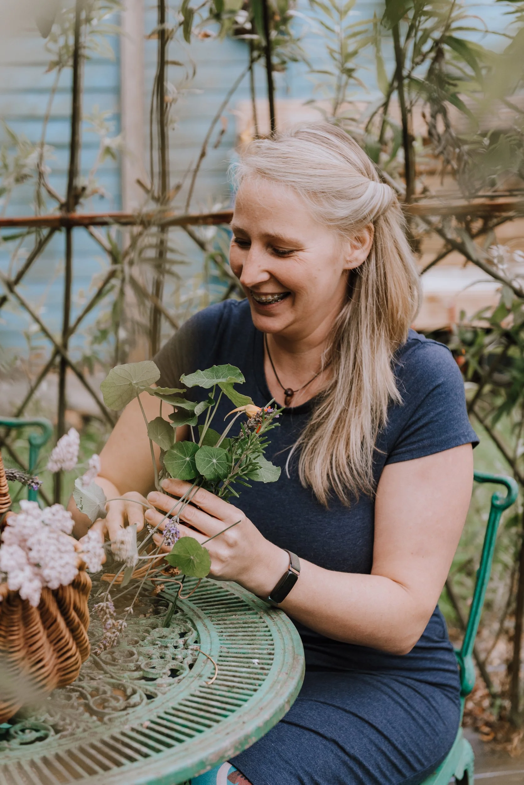 Carly, Nature In Me. Carly is dressed in blue and is arranging plants from her garden.