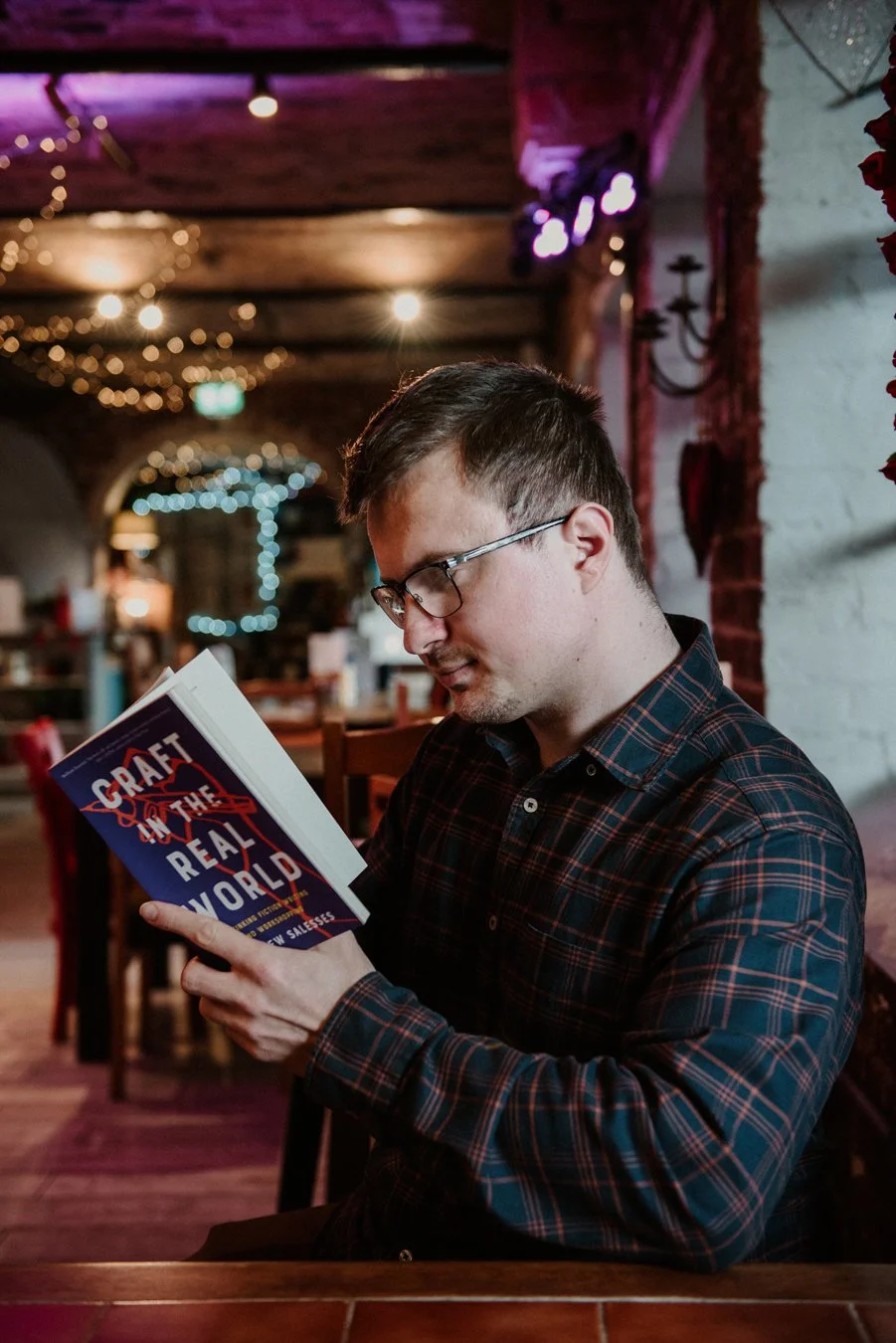 A man reads a book in a cosy cafe.