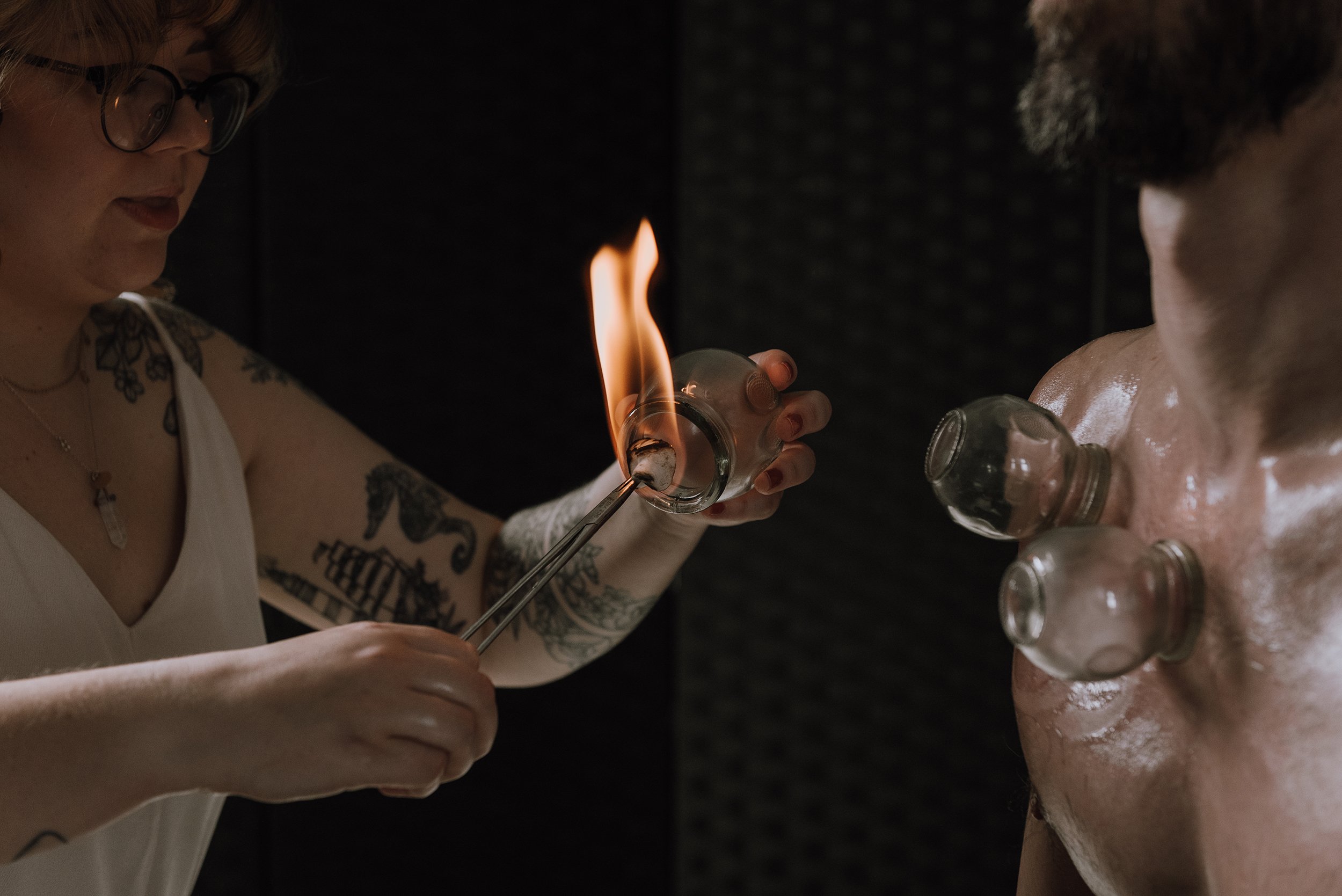 Woman dressed in white putting a flame inside a cup for fire cupping.
