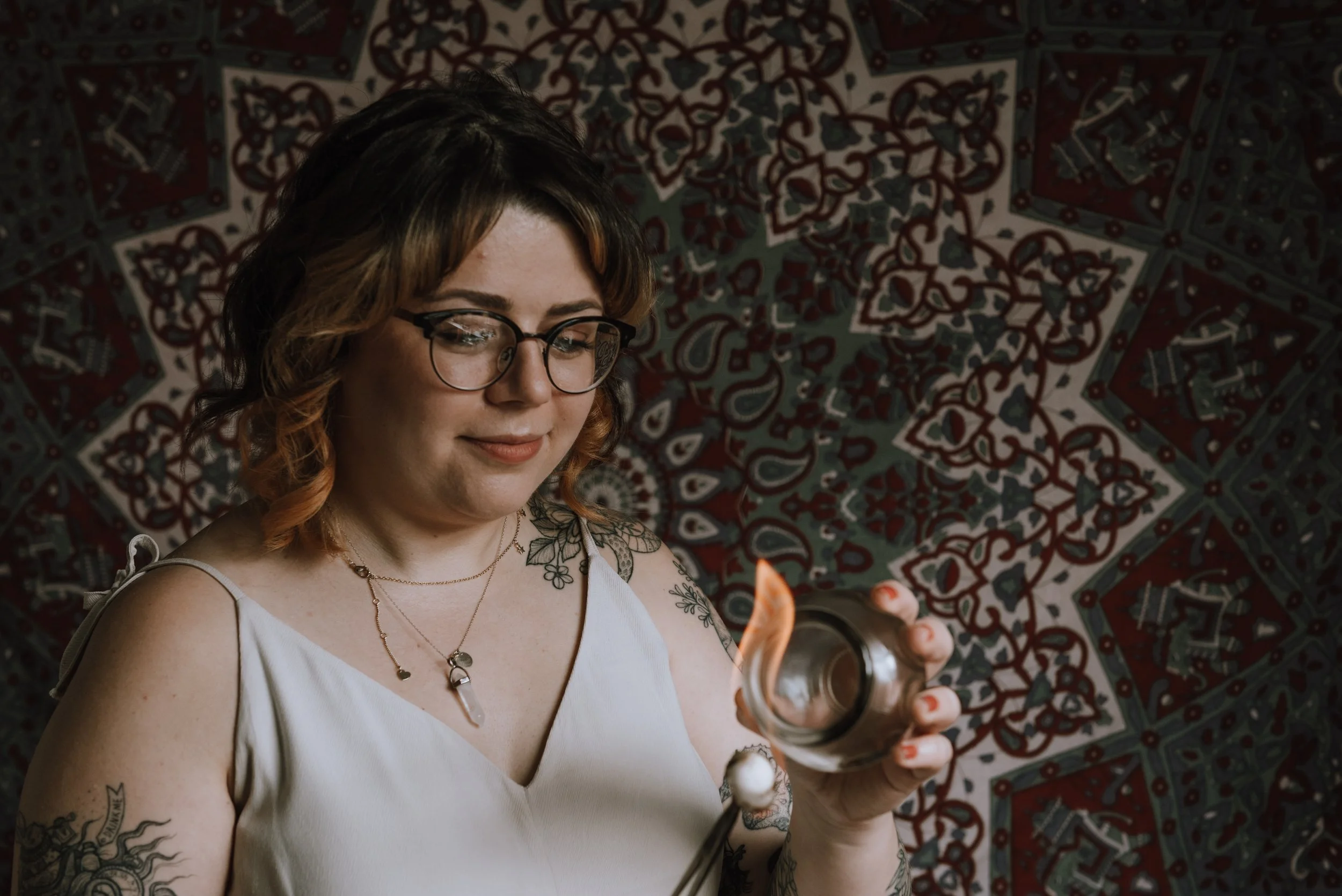 Woman dressed in white holding up a flame to a cup